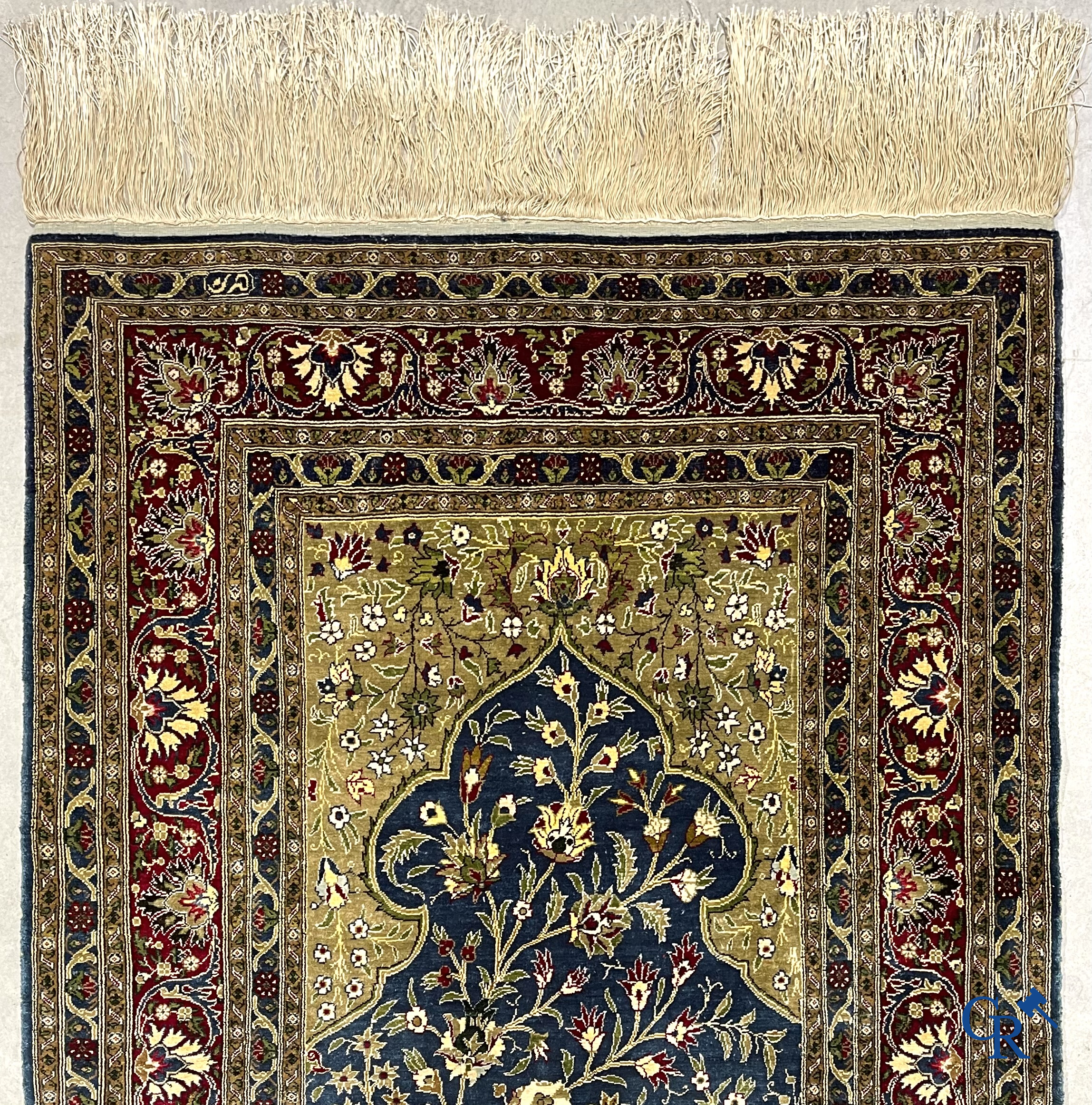 Oosterse tapijten. Een uiterst fijn geknoopt zijden tapijt met floraal decor op donker blauwe achtergrond en gouddraad.