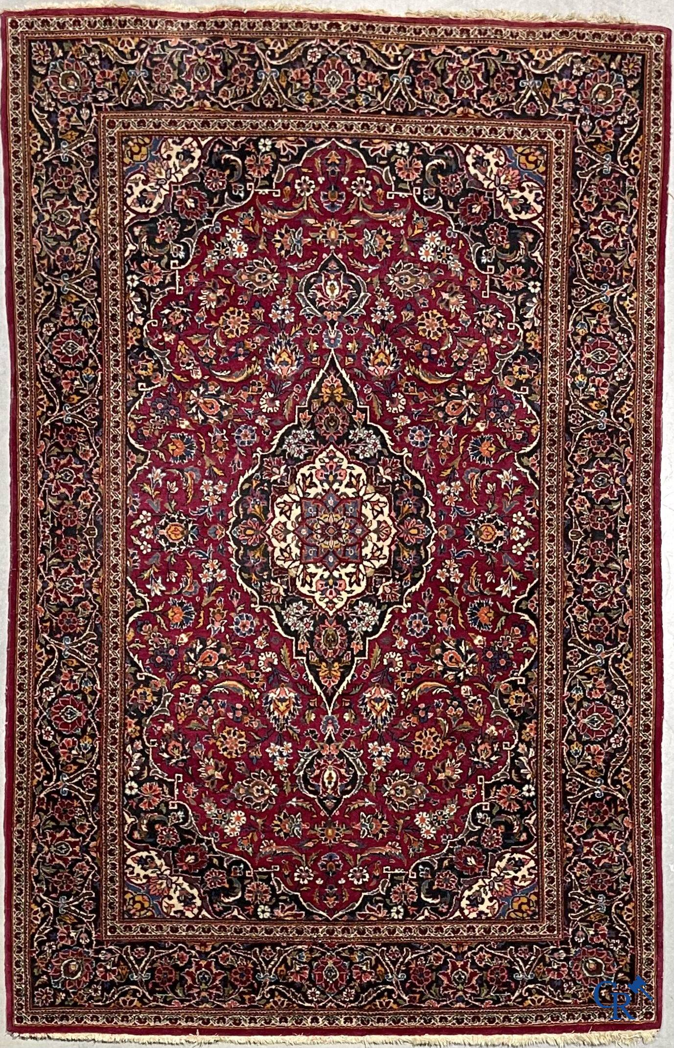 Oosterse tapijten. Een handgeknoopt oosters tapijt met floraal decor op rode achtergrond.