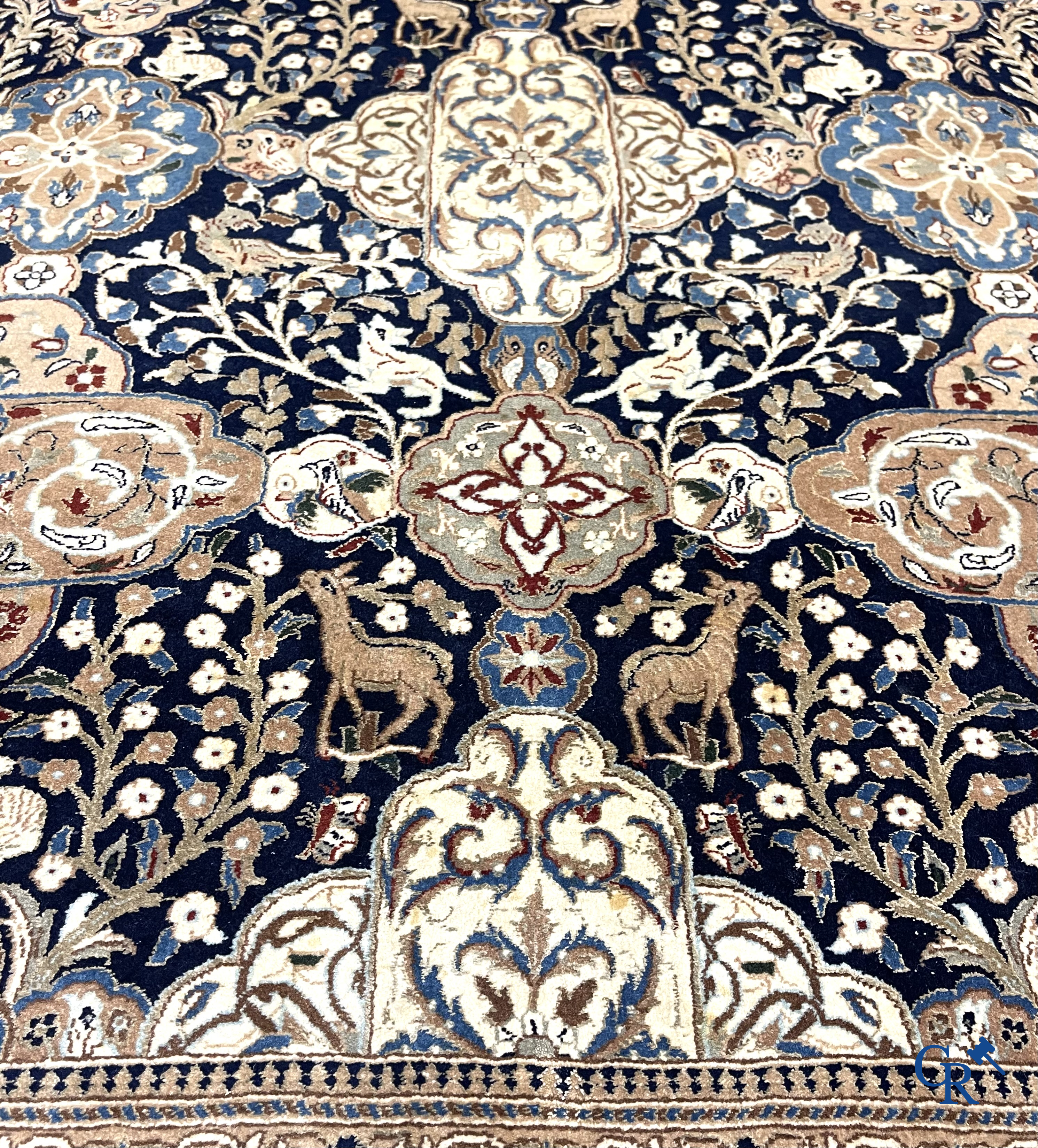 Oosterse tapijten. Een handgeknoopt tapijt met wouddieren en bloemen.