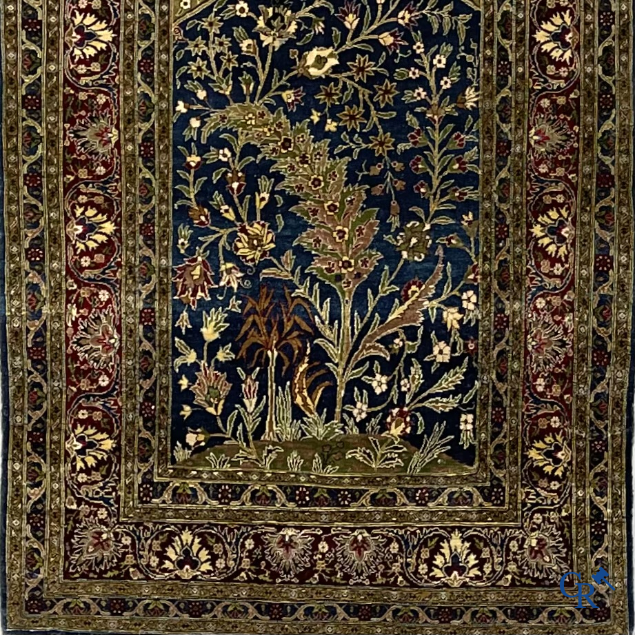 Oosterse tapijten. Een uiterst fijn geknoopt zijden tapijt met floraal decor op donker blauwe achtergrond en gouddraad.