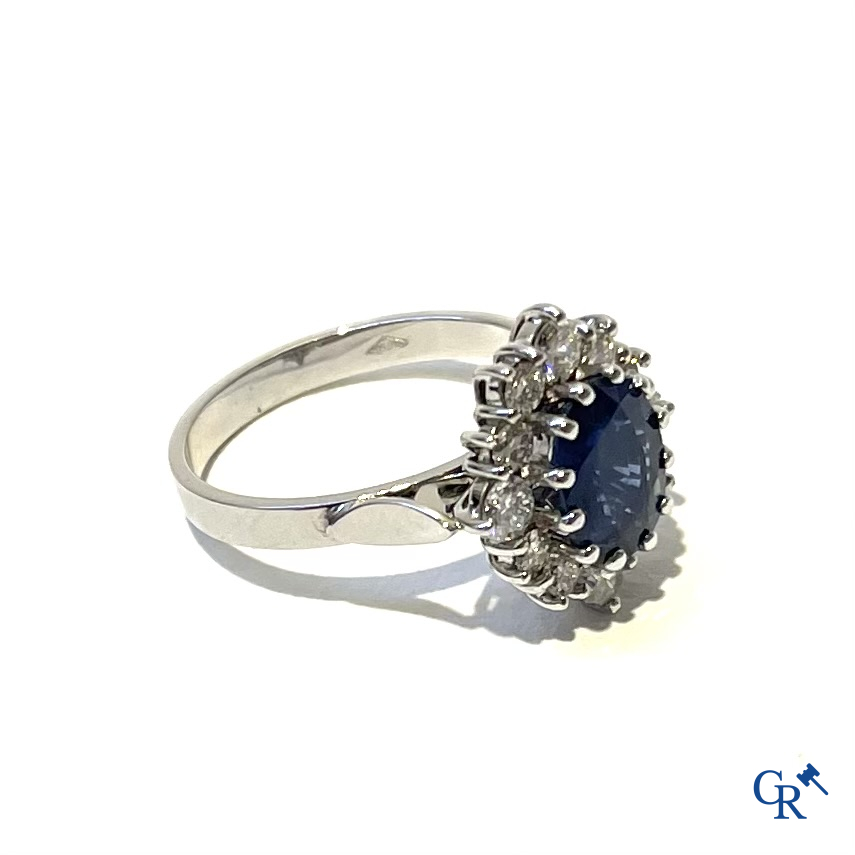 Jewellery. Ring in white gold 750°/00 set with a central blue sapphire surrounded by 12 small diamonds.