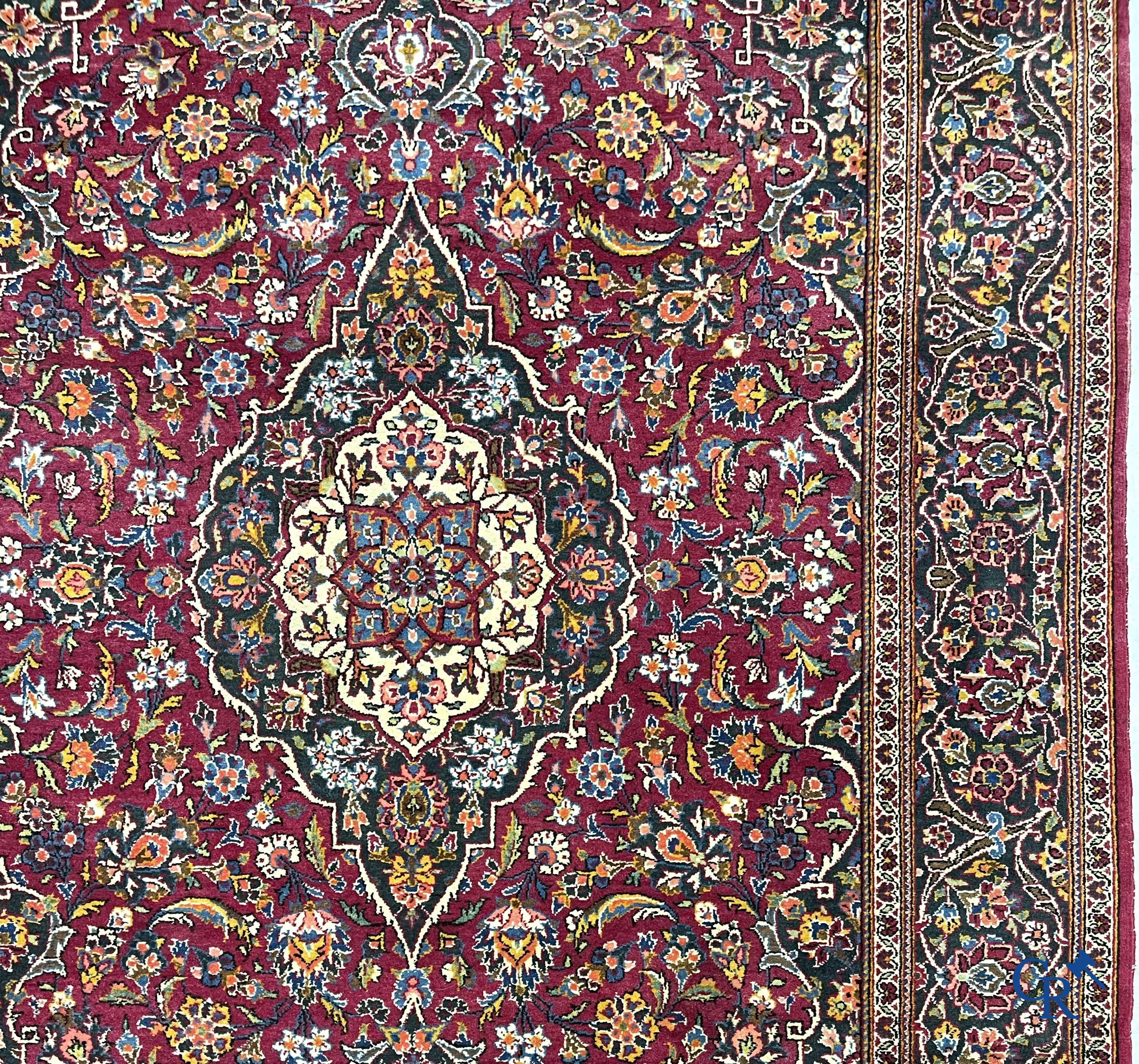 Oosterse tapijten. Een handgeknoopt oosters tapijt met floraal decor op rode achtergrond.