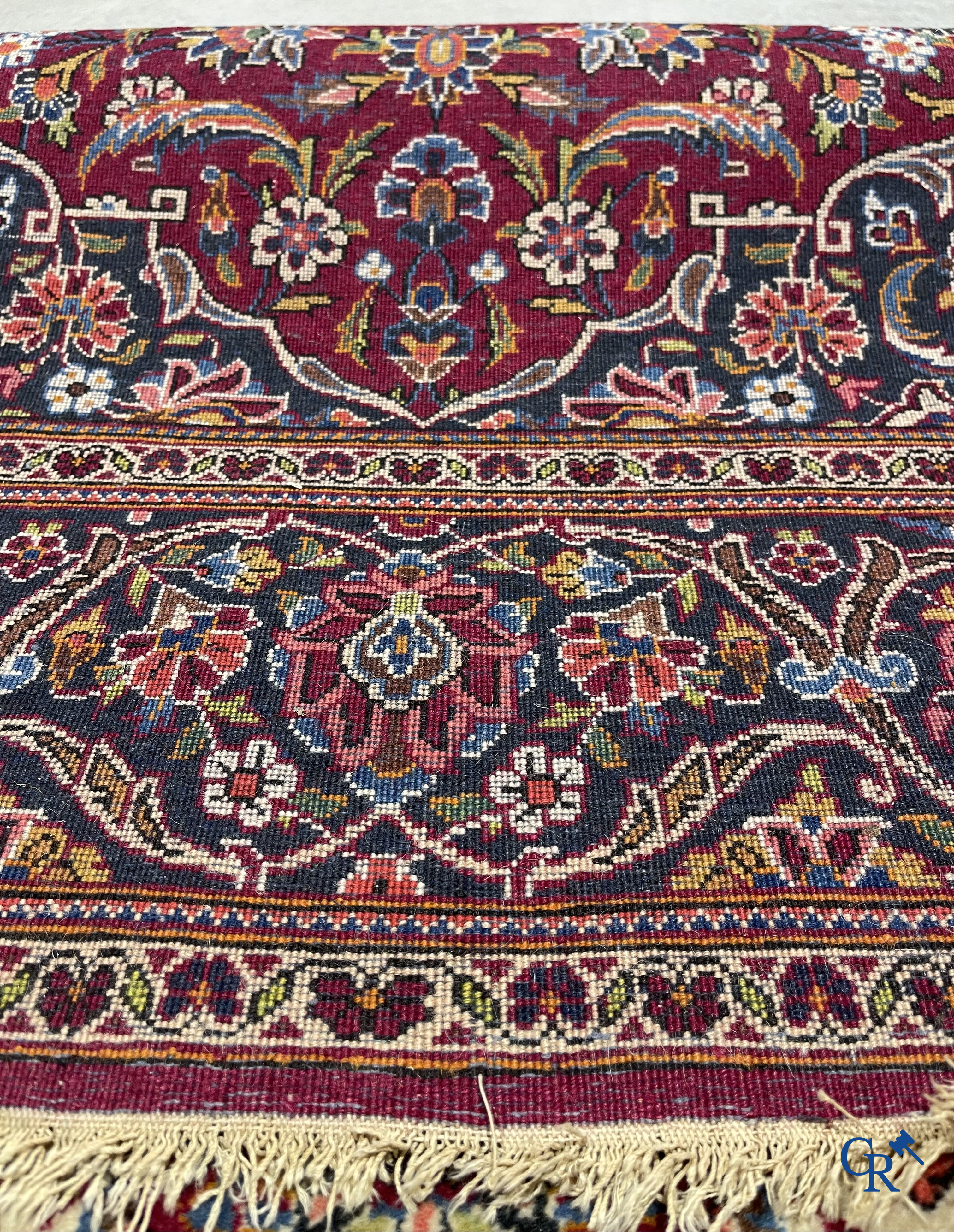 Oosterse tapijten. Een handgeknoopt oosters tapijt met floraal decor op rode achtergrond.