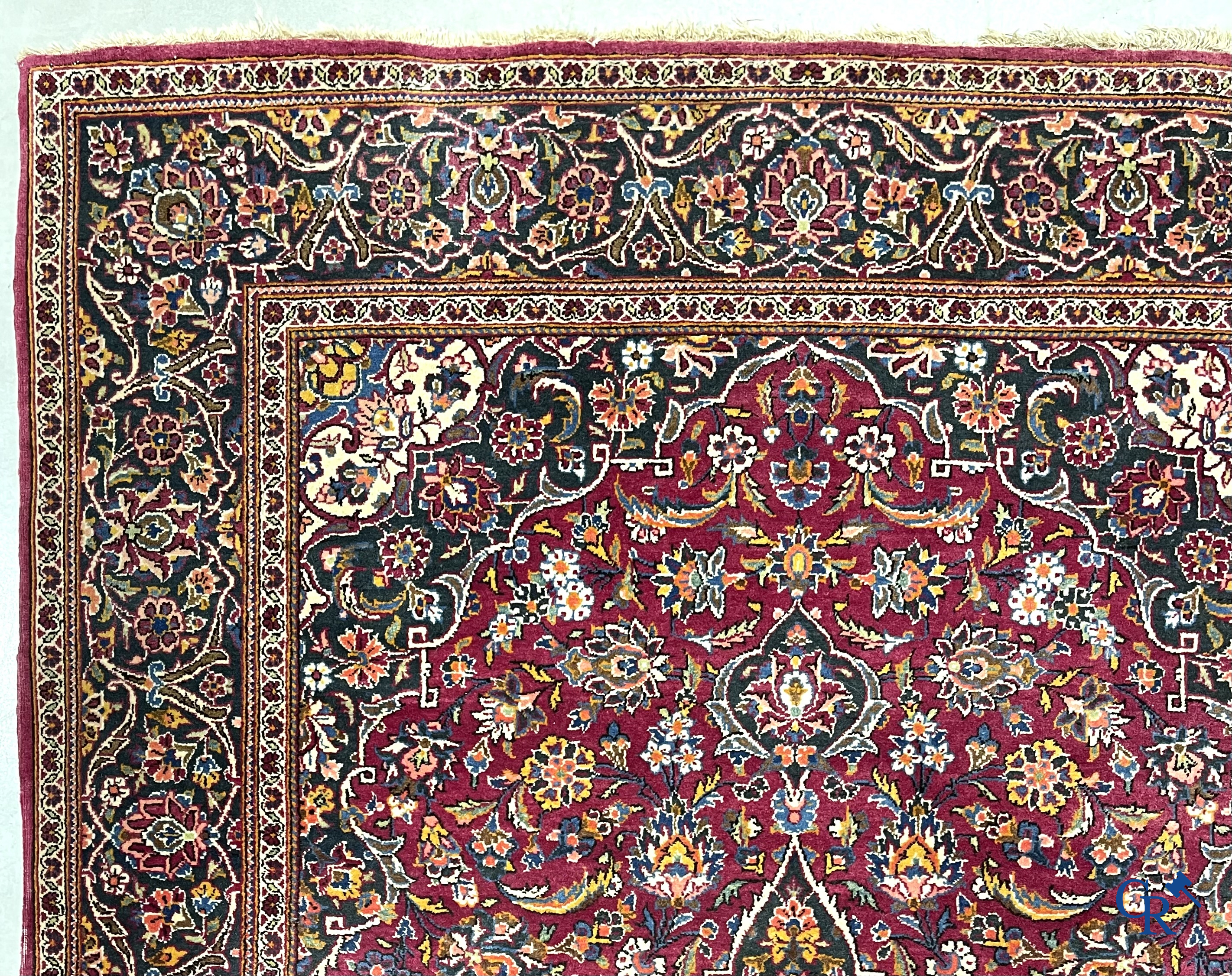 Oosterse tapijten. Een handgeknoopt oosters tapijt met floraal decor op rode achtergrond.