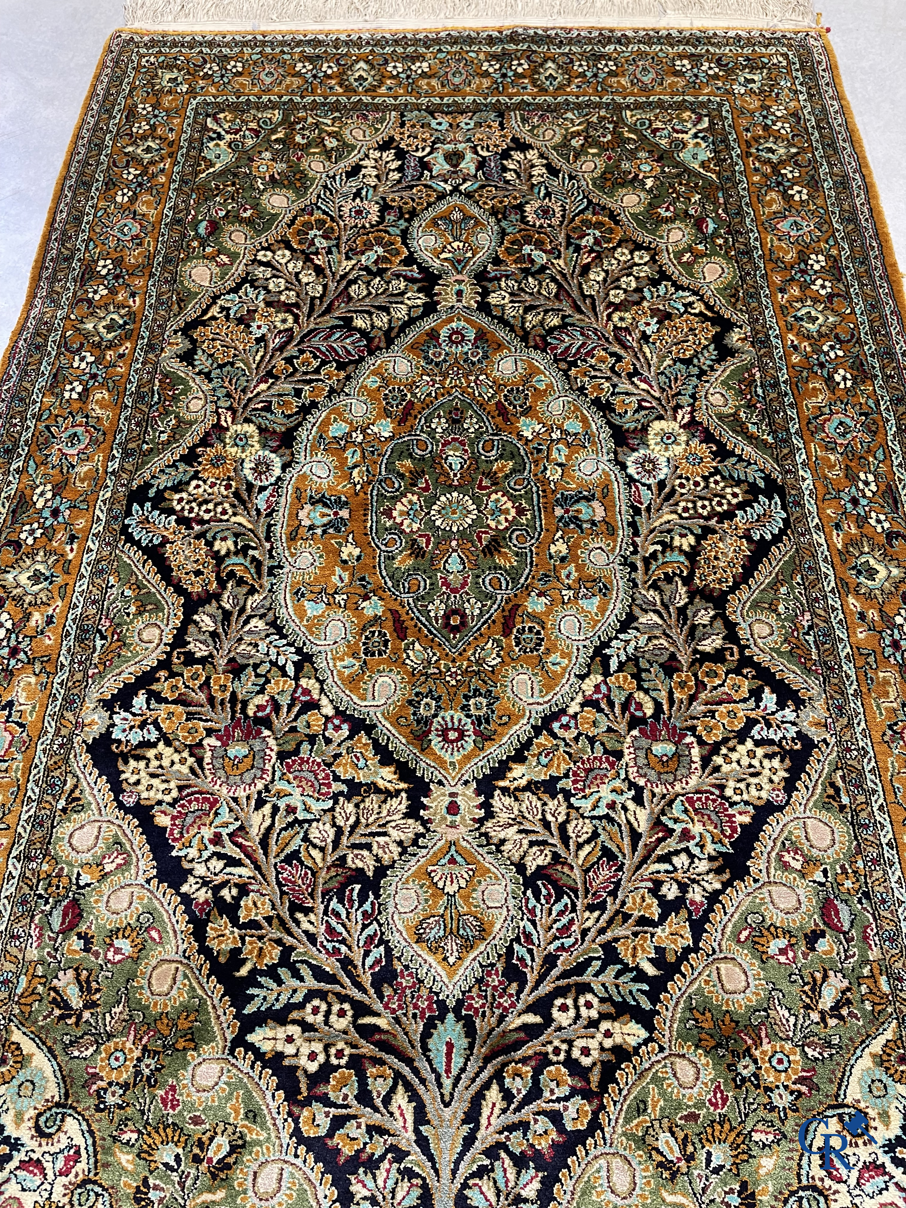 Oriental carpets. Hand-knotted silk carpet with floral decor on an orange background.