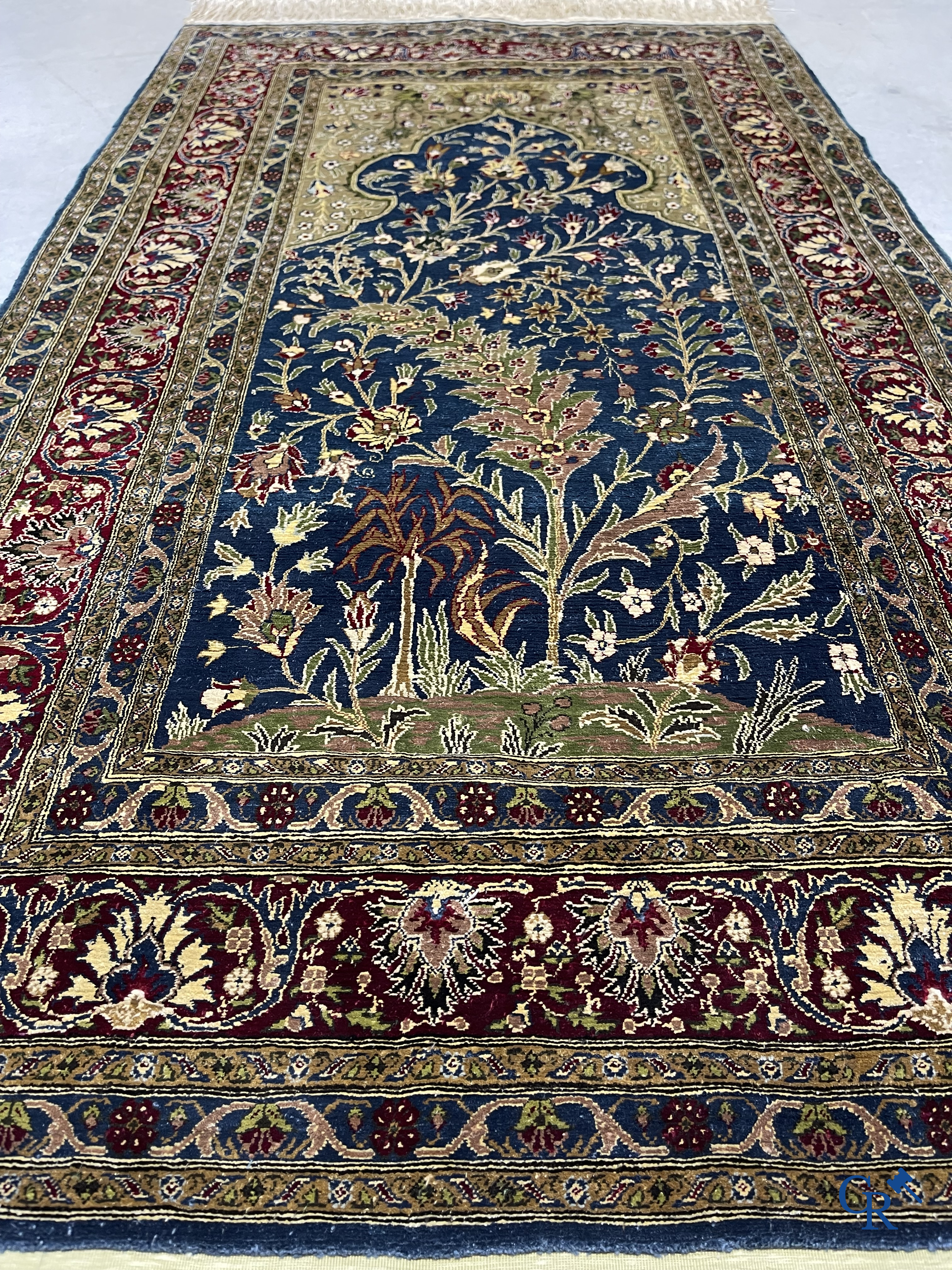 Oosterse tapijten. Een uiterst fijn geknoopt zijden tapijt met floraal decor op donker blauwe achtergrond en gouddraad.