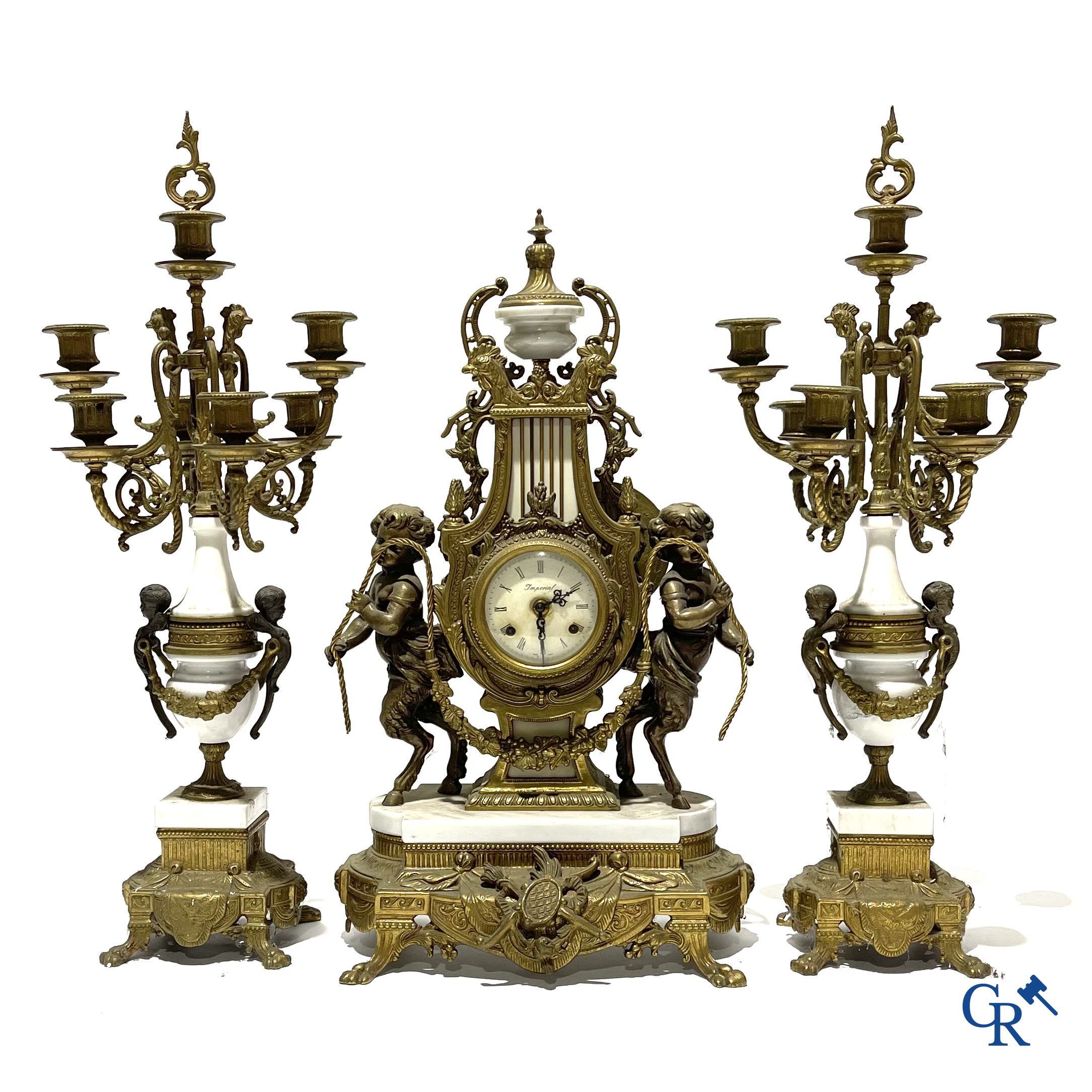 Groot 3-delige schouwgarnituur in brons en marmer met putti op bokkenpoten. LXVI-stijl. 20ste eeuw.<br />
