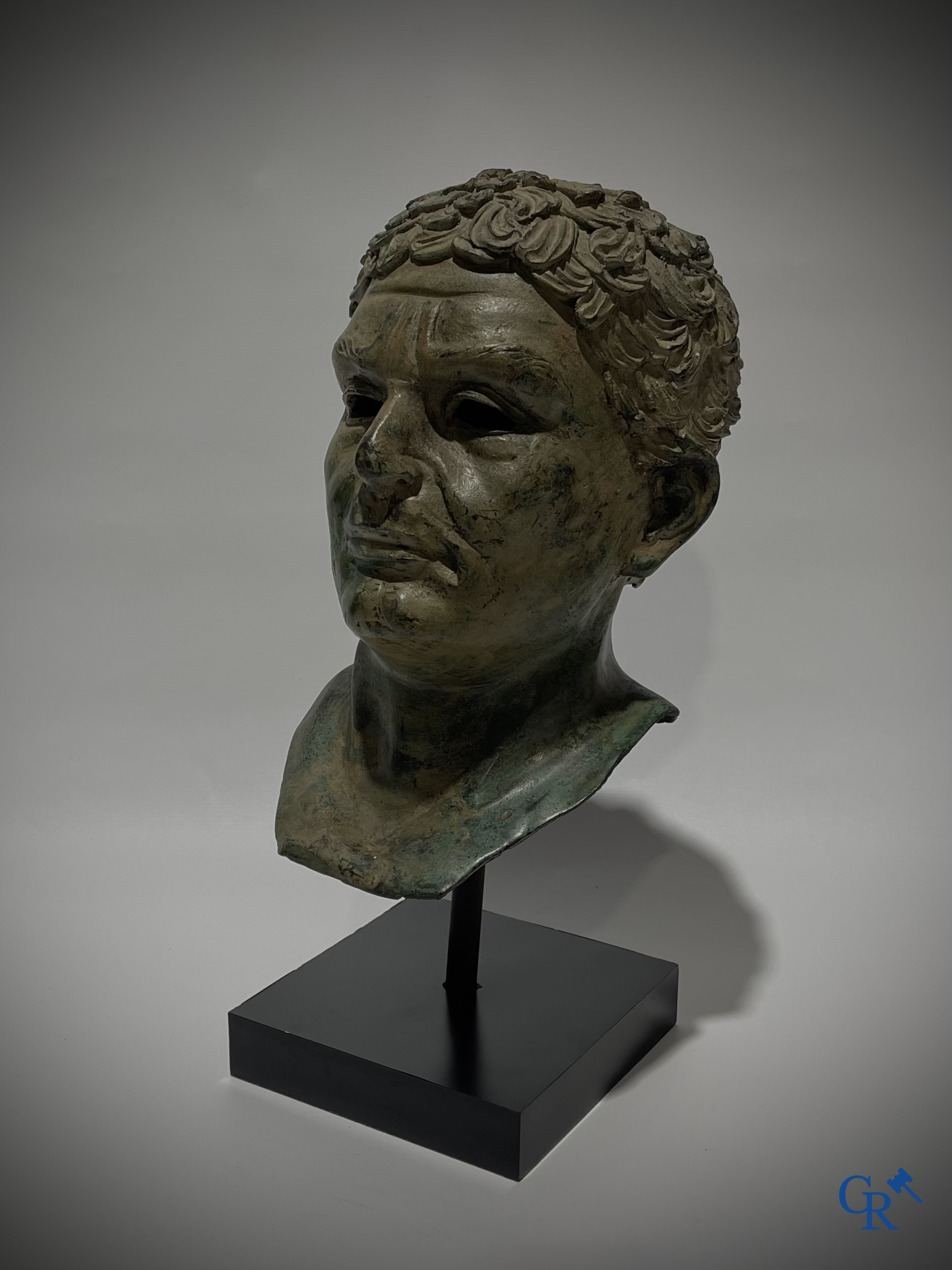 Een bronzen hoofd naar de antieke stijl gemonteerd op een sokkel.