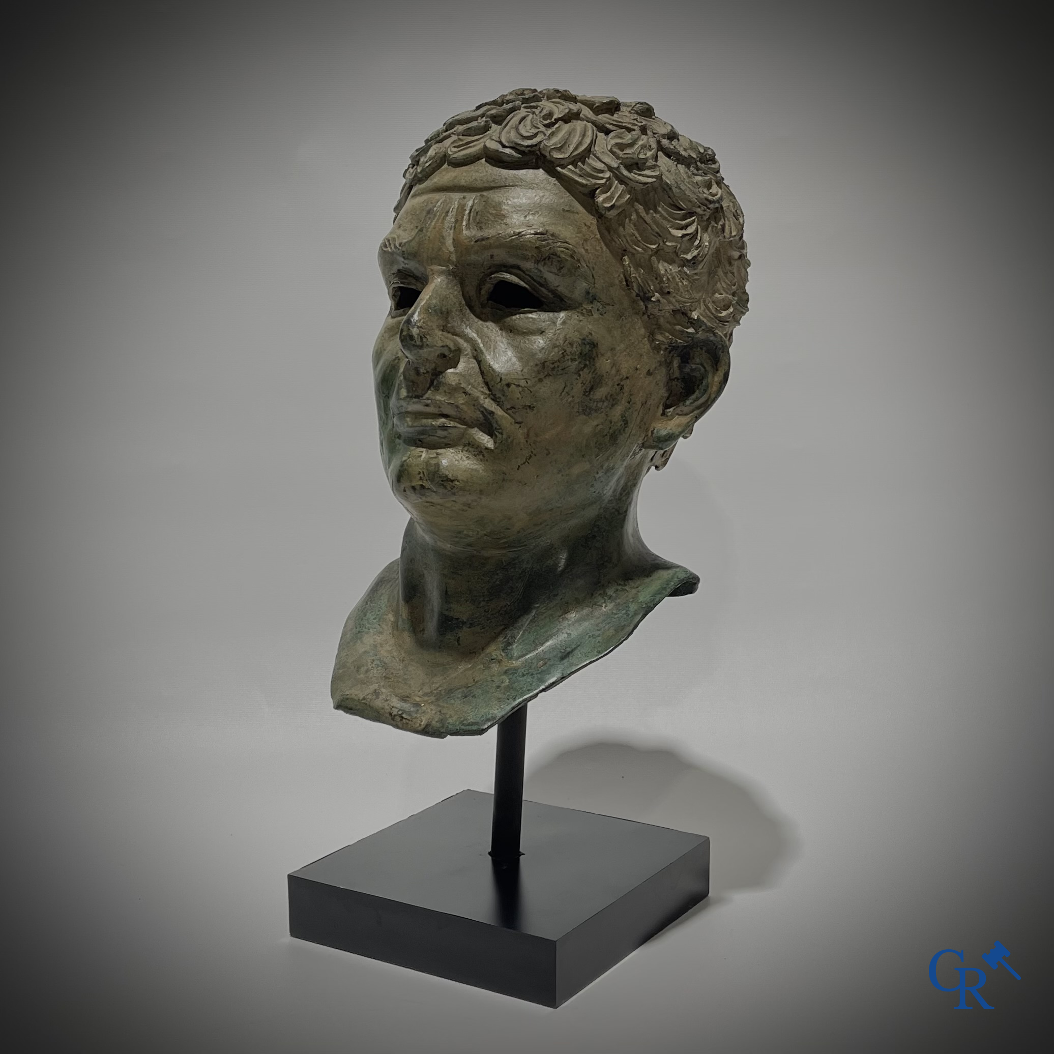 Een bronzen hoofd naar de antieke stijl gemonteerd op een sokkel.