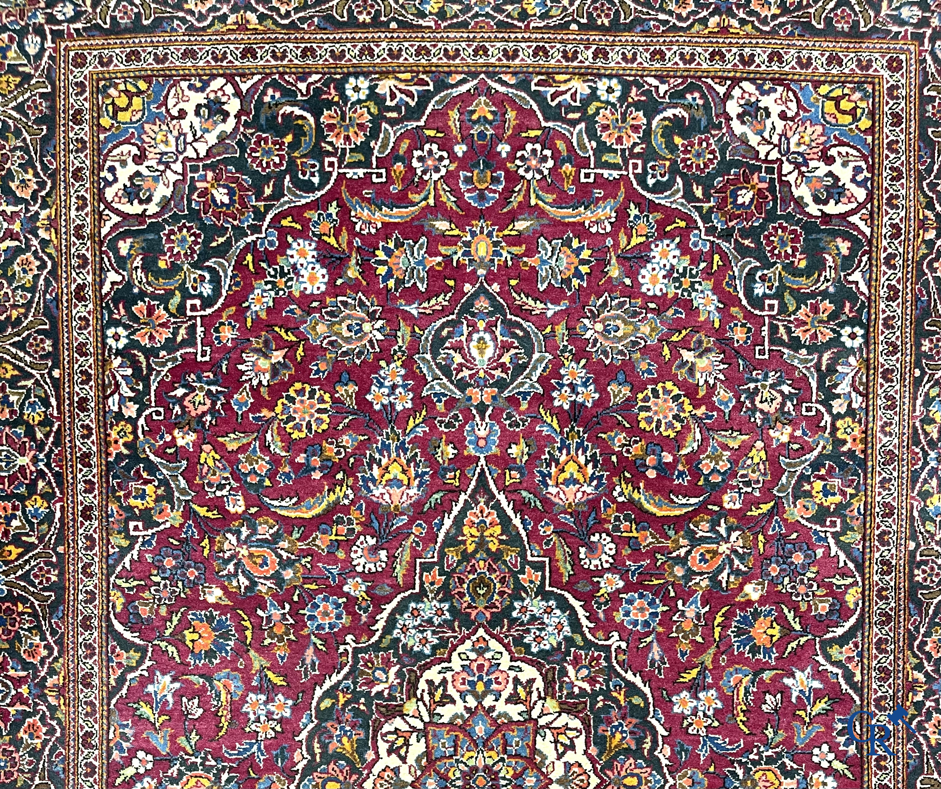 Oosterse tapijten. Een handgeknoopt oosters tapijt met floraal decor op rode achtergrond.