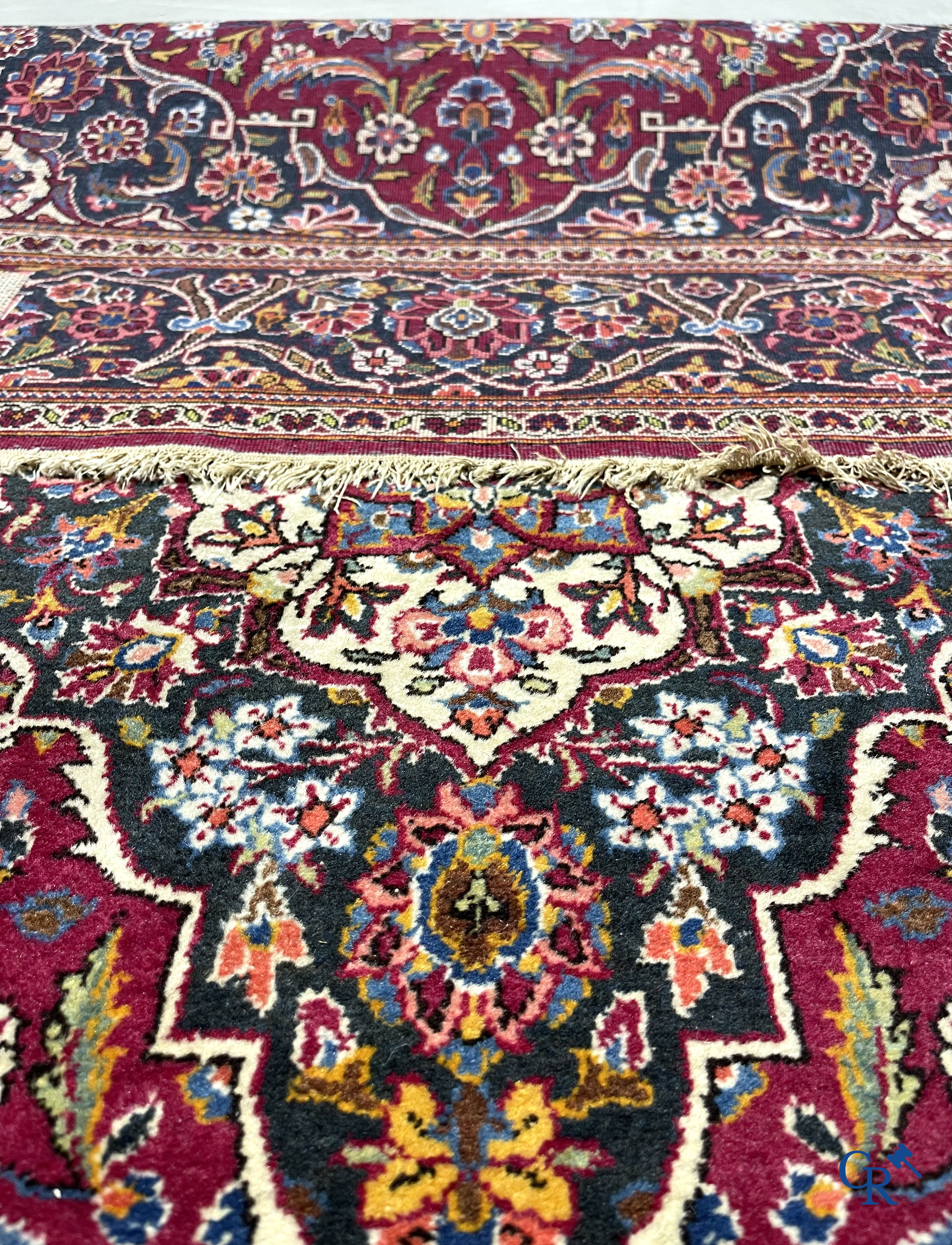 Oosterse tapijten. Een handgeknoopt oosters tapijt met floraal decor op rode achtergrond.