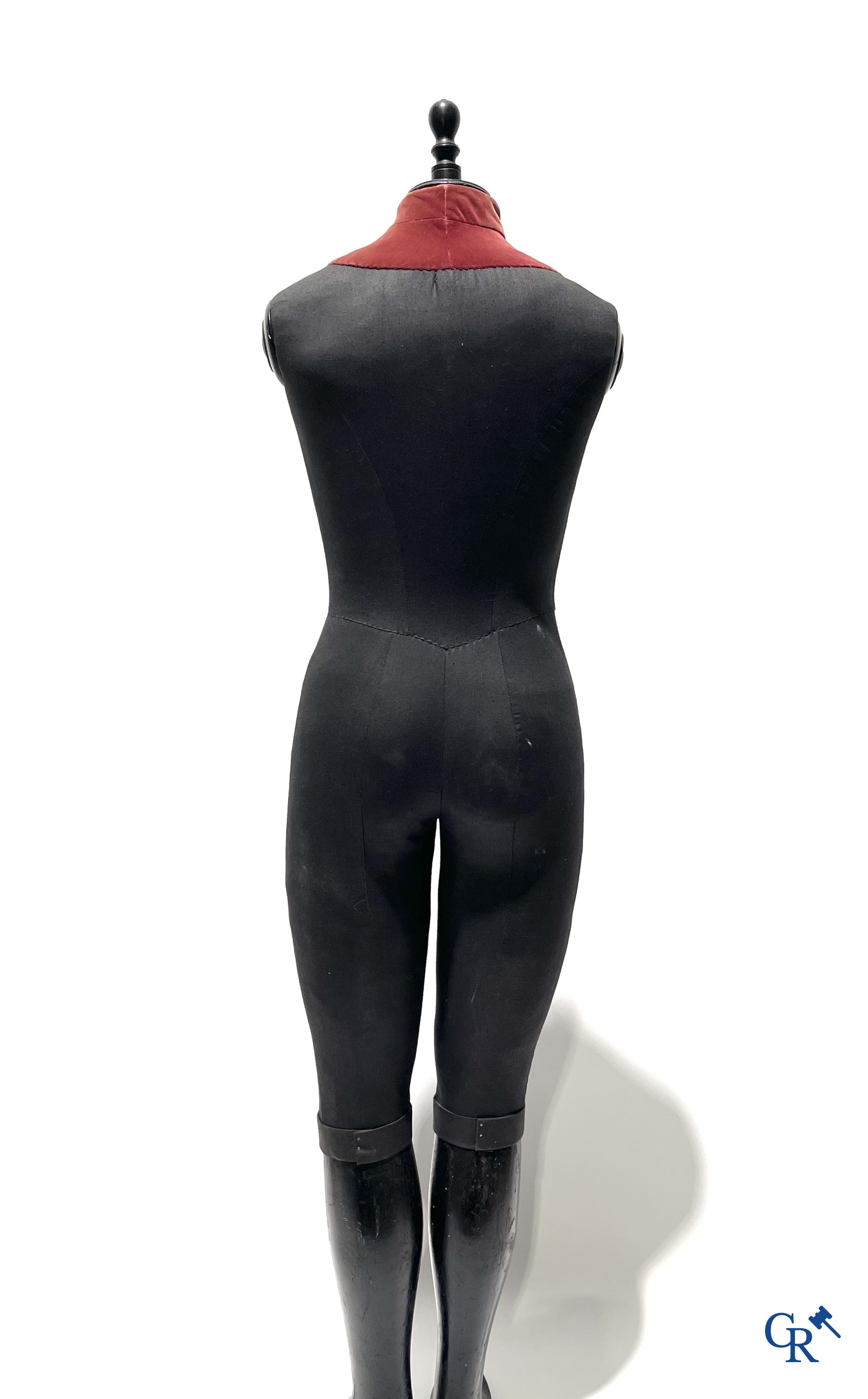 Een kindermannequin met houten laarzen en zwarte stof in de stijl van Stockman. Circa 1900.