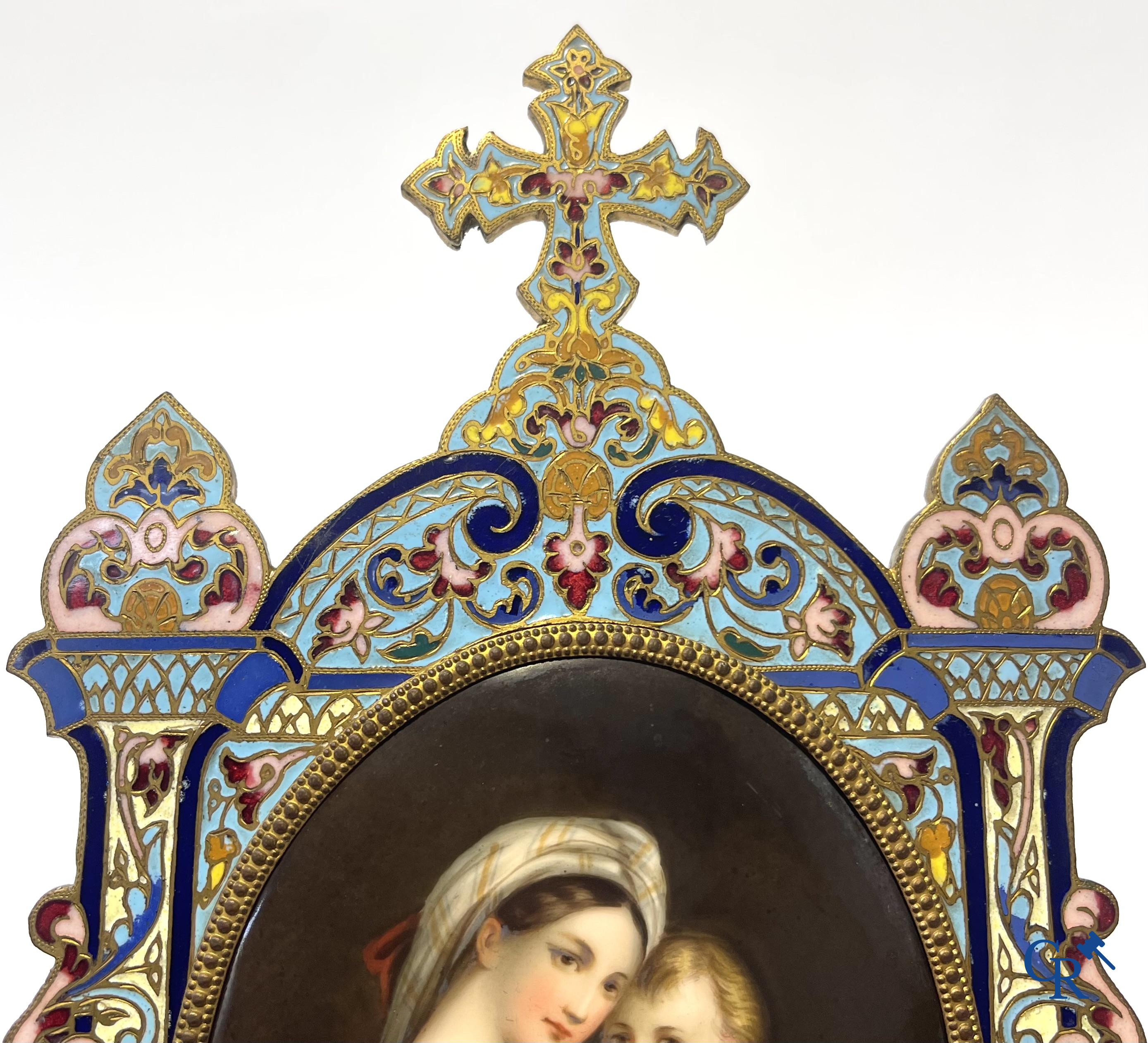 Religieuze objecten. Een grote kader in brons en champlevé emaille met ingewerkte plakket in porselein. 19e eeuw.