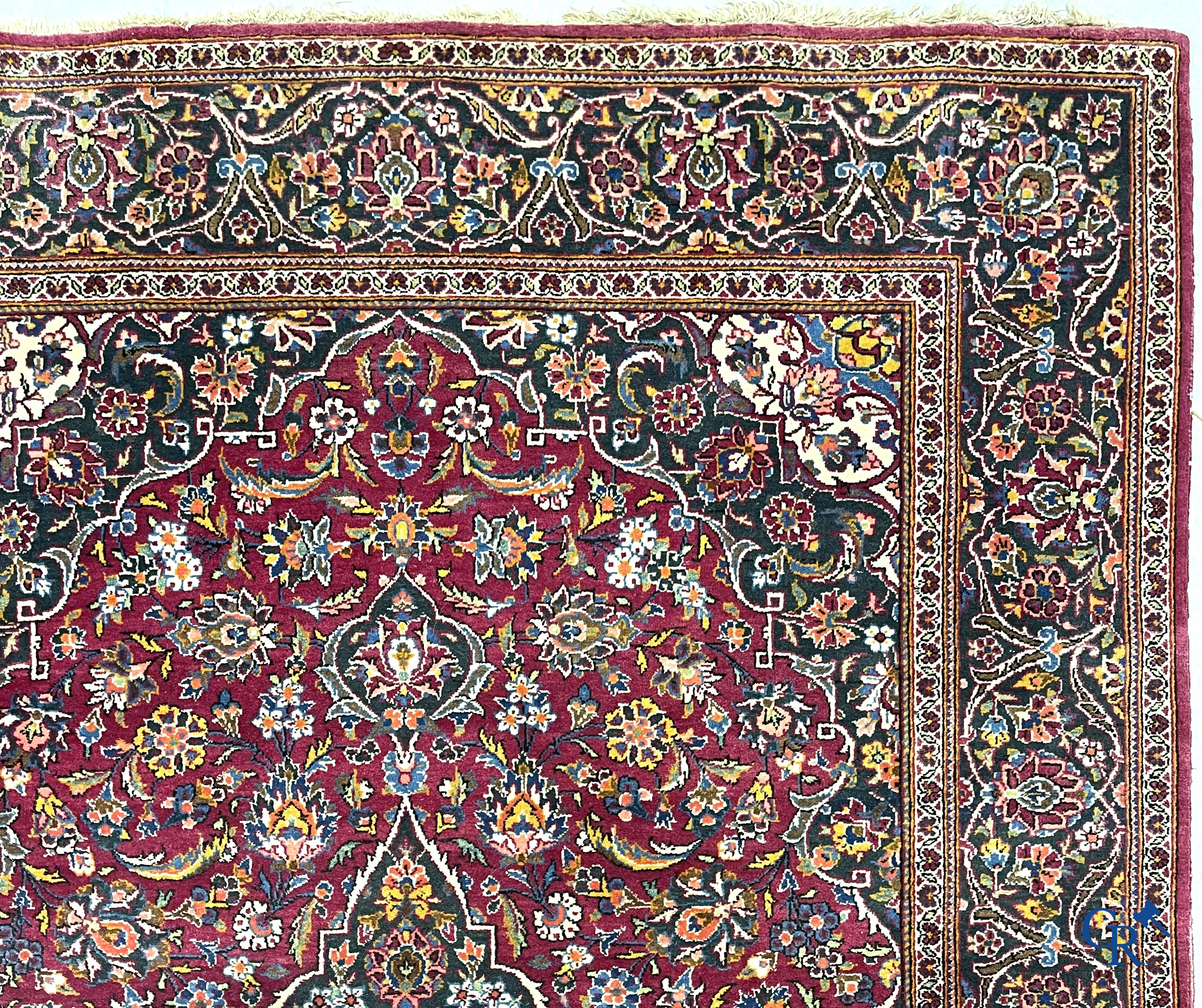 Oosterse tapijten. Een handgeknoopt oosters tapijt met floraal decor op rode achtergrond.