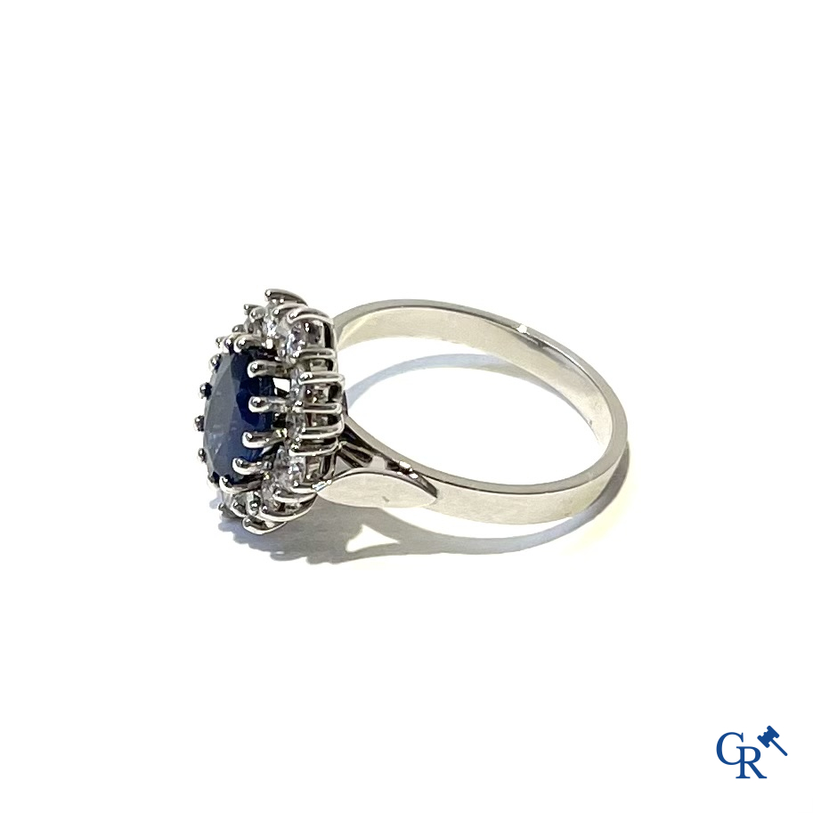 Jewellery. Ring in white gold 750°/00 set with a central blue sapphire surrounded by 12 small diamonds.