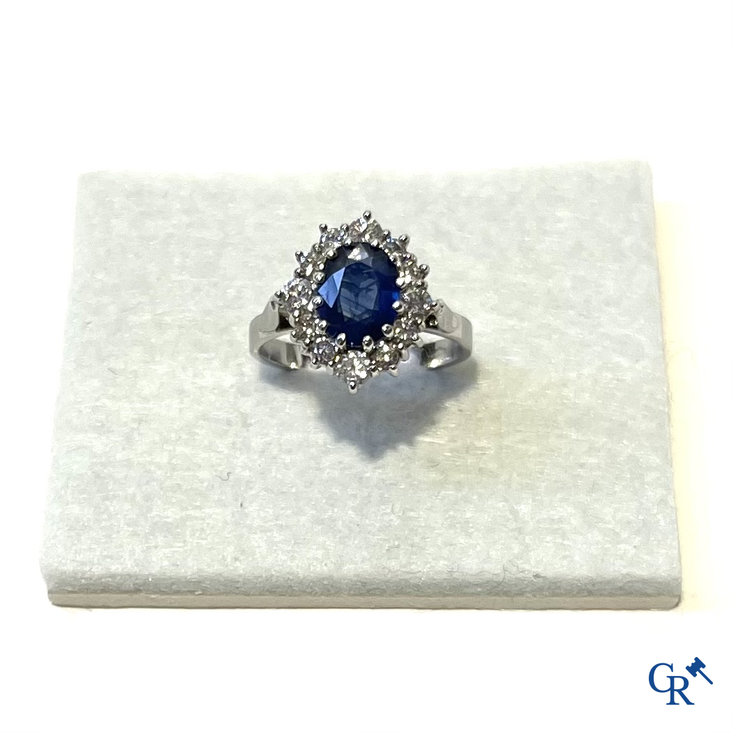 Jewellery. Ring in white gold 750°/00 set with a central blue sapphire surrounded by 12 small diamonds.
