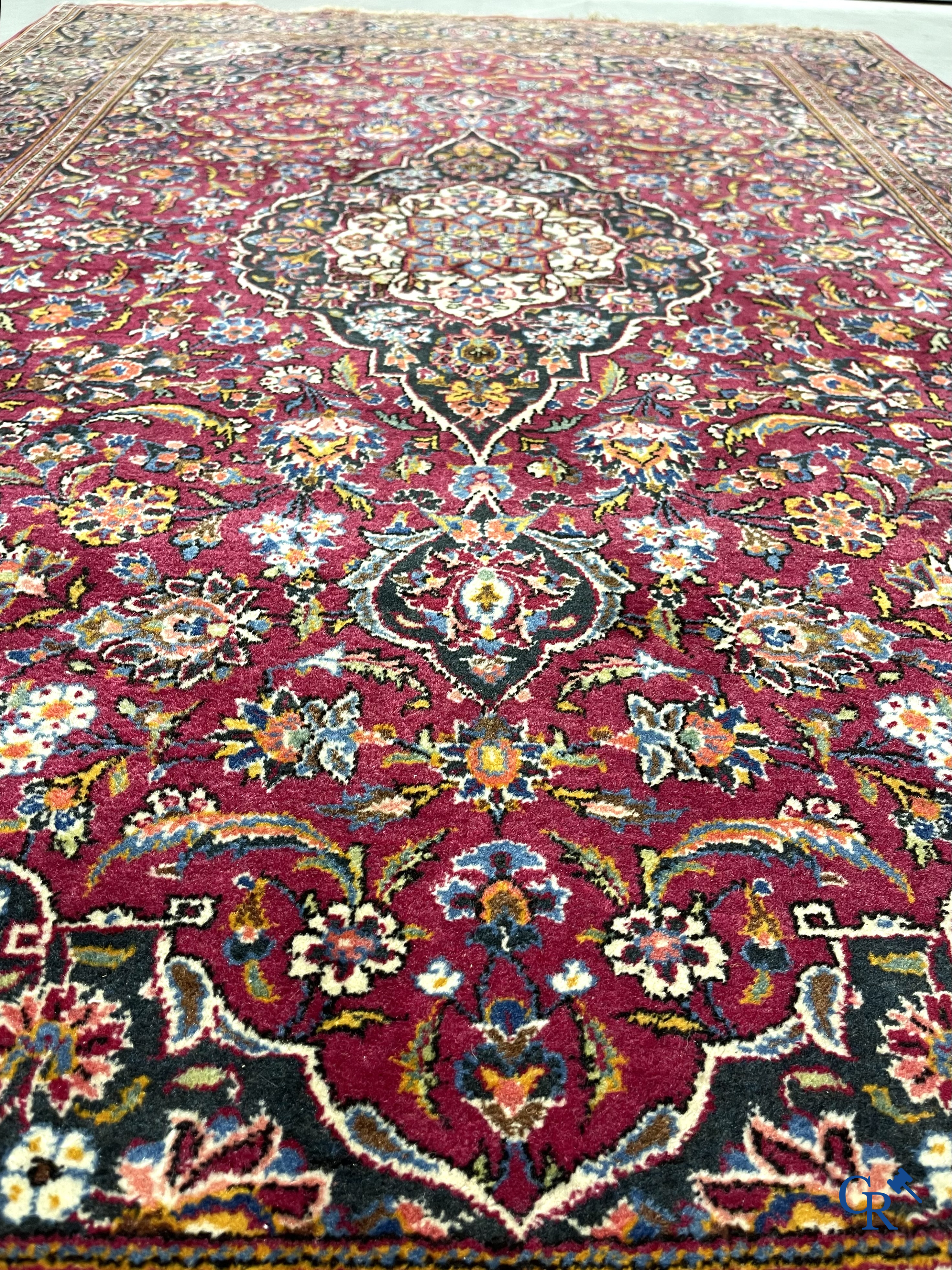 Oosterse tapijten. Een handgeknoopt oosters tapijt met floraal decor op rode achtergrond.