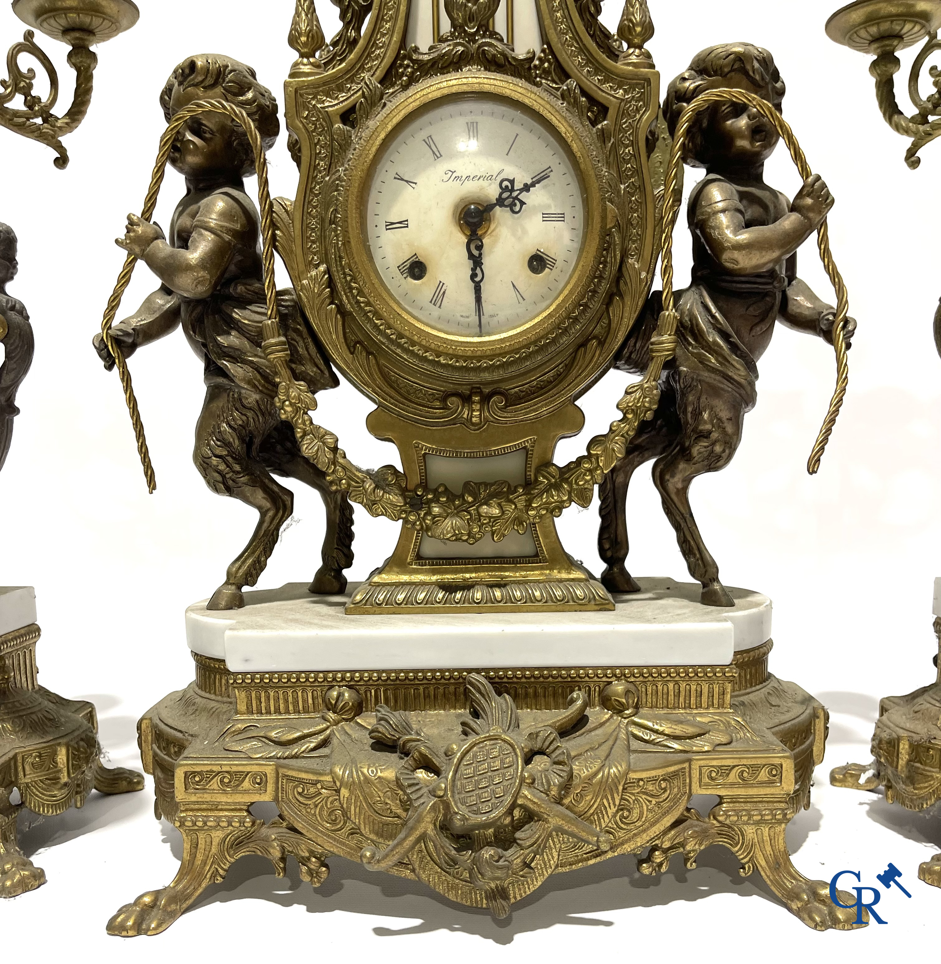 Groot 3-delige schouwgarnituur in brons en marmer met putti op bokkenpoten. LXVI-stijl. 20ste eeuw.<br />
