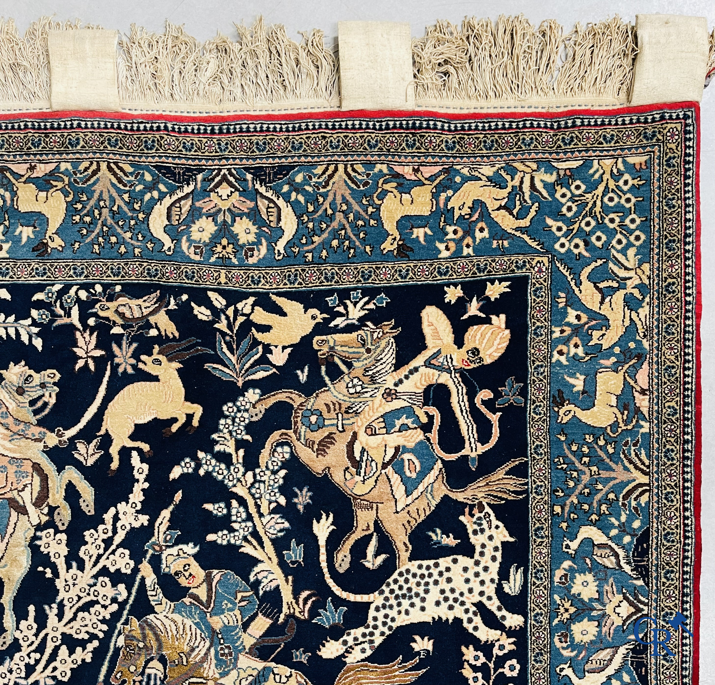 Oosterse tapijten. Ghoum, een fijn geknoopt Perzisch tapijt met ruiters te paard op een donkerblauwe achtergrond.