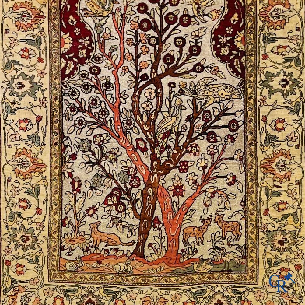 Oriental carpets, a hand-knotted carpet in silk with forest animals in a floral decor on a background in gold thread.