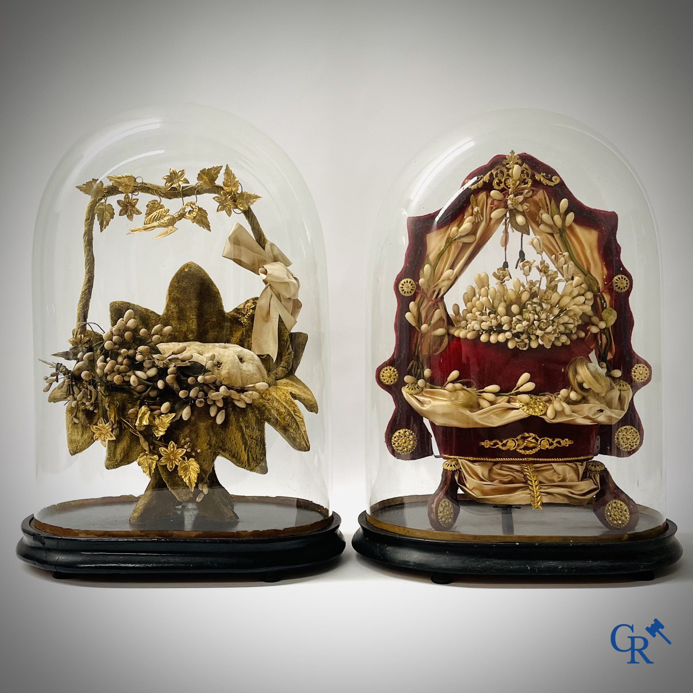 2 globes in glas met een bruidsboeket op sokkel bewerkt met ornamenten in vergulde messing. Circa 1900.
