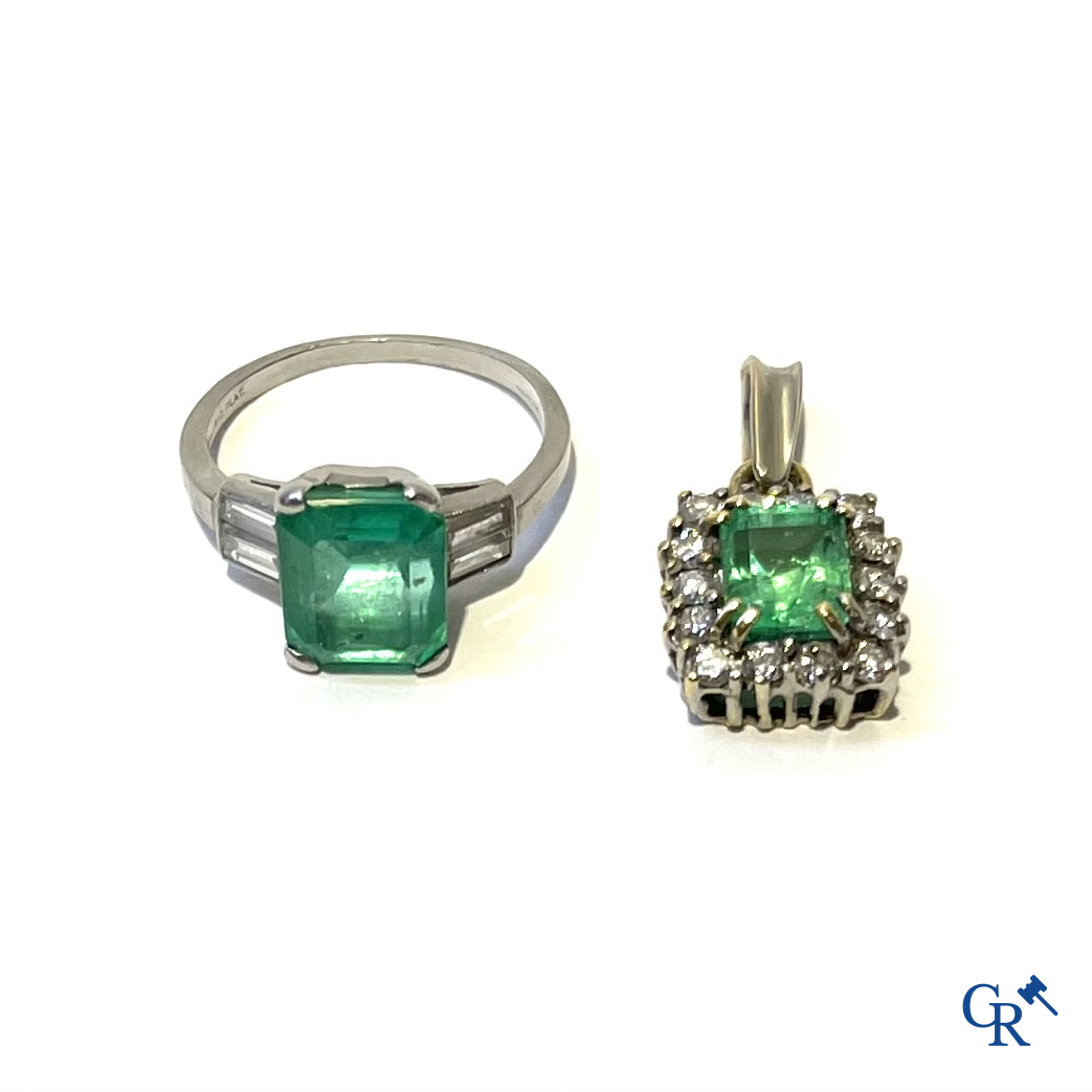 Juwelen. Een platina ring met smaragd en diamanten en een hanger in witgoud 750°/00 met smaragd en 14 diamanten.