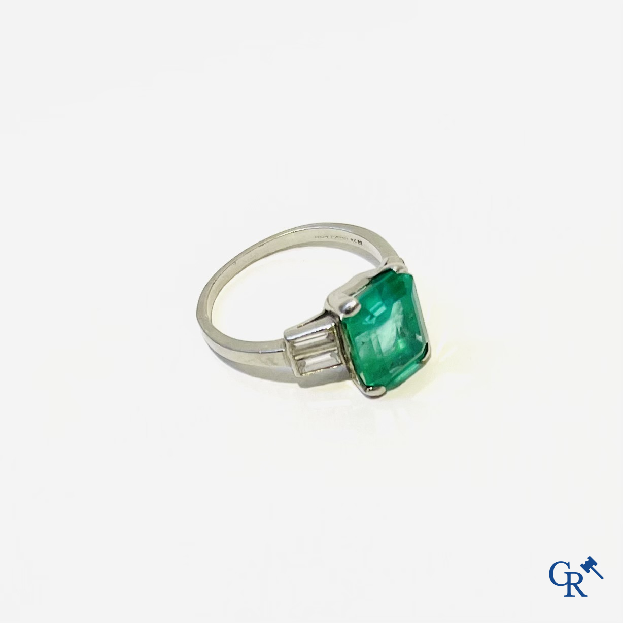 Juwelen. Een platina ring met smaragd en diamanten en een hanger in witgoud 750°/00 met smaragd en 14 diamanten.