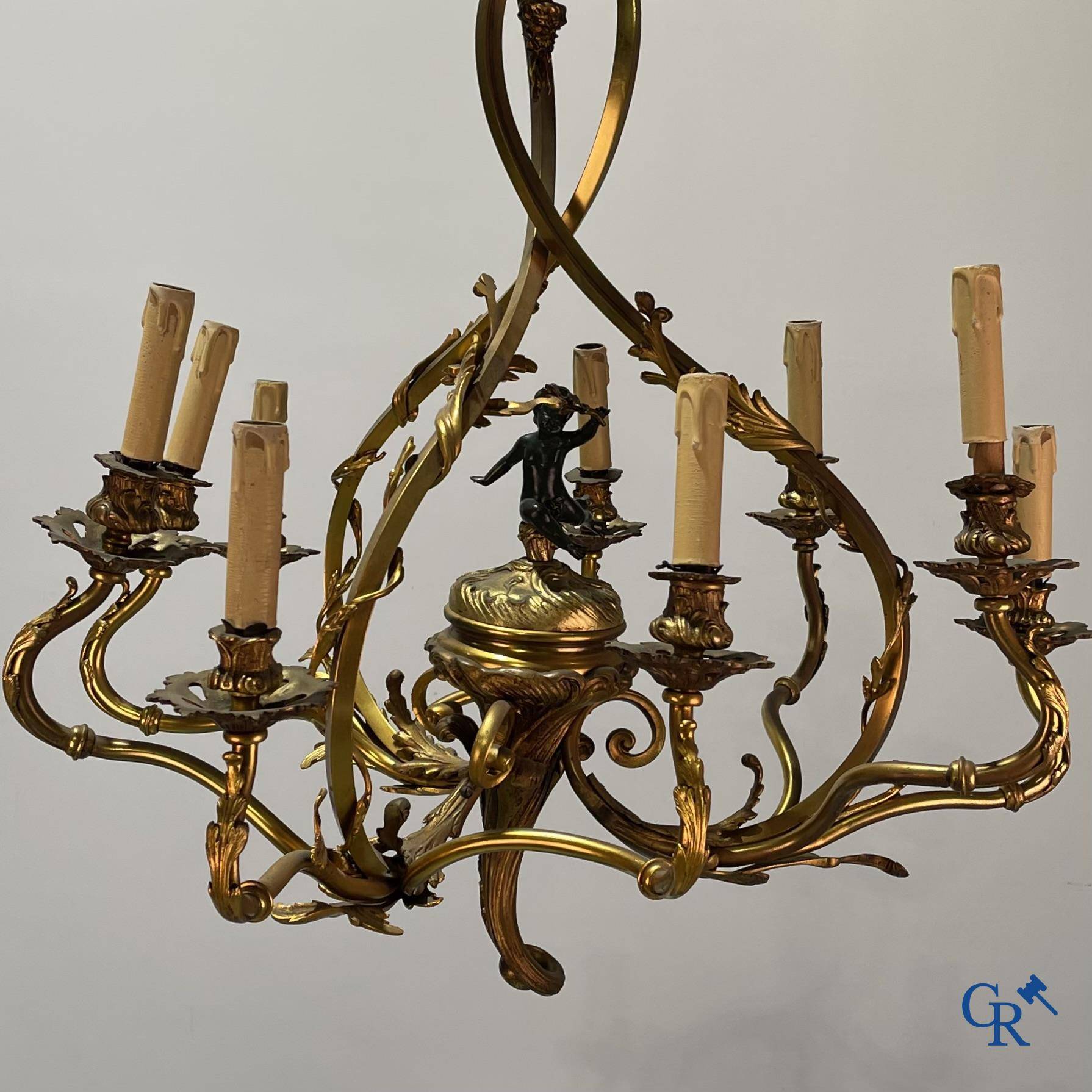 A bronze chandelier with putti and 9 light points in LXV style. Circa 1920.