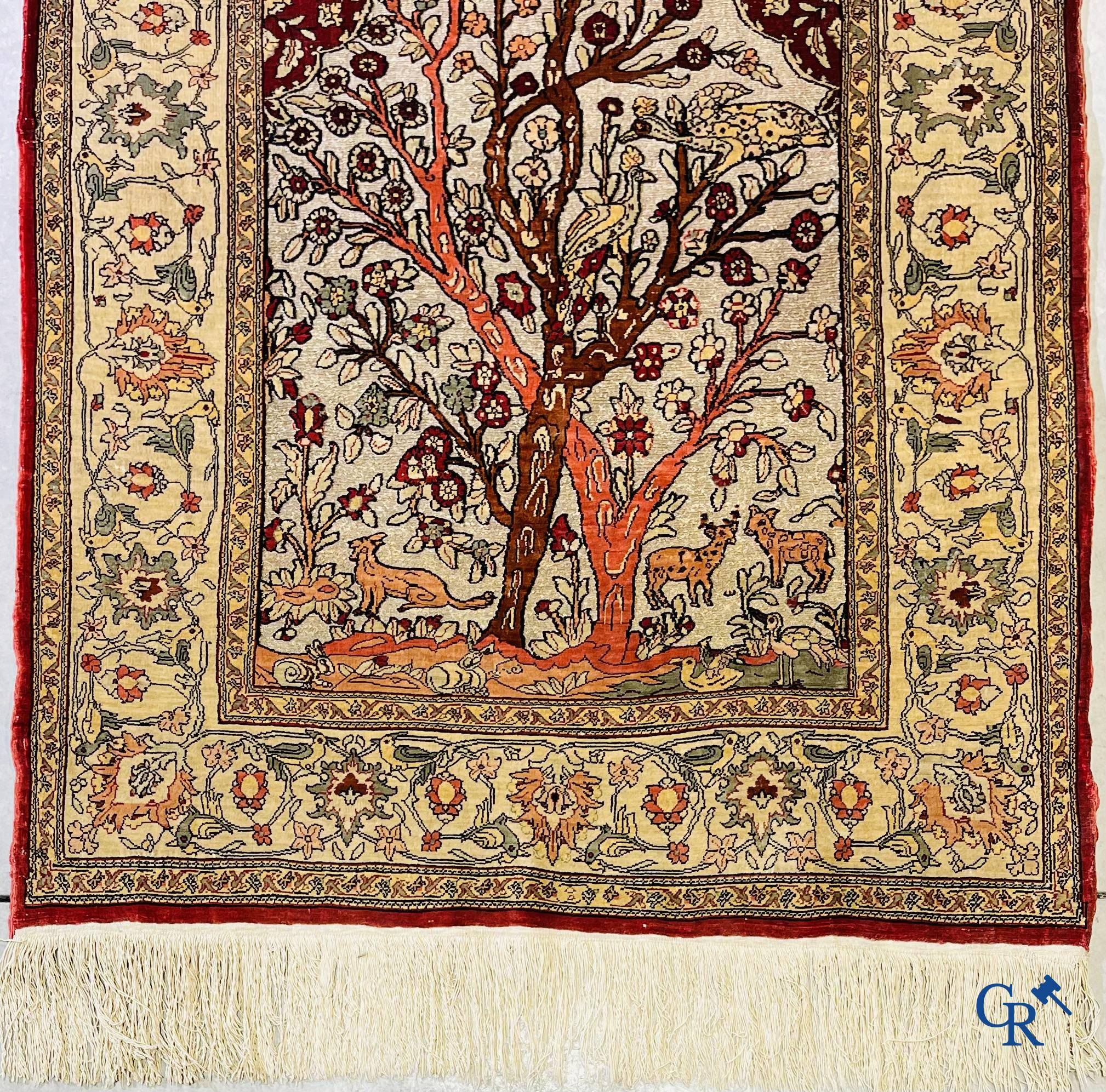 Oriental carpets, a hand-knotted carpet in silk with forest animals in a floral decor on a background in gold thread.