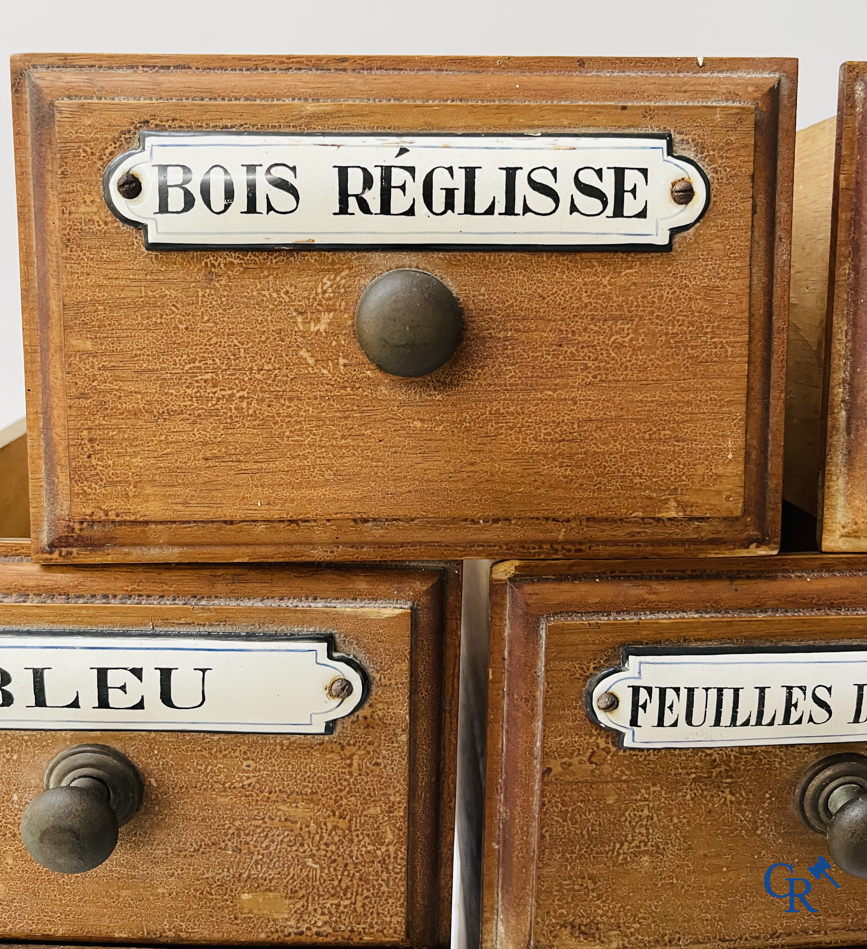 14 laden met emaille bordjes voor kruiden, specerijen en andere afkomstig van een winkelmeubel. Circa 1920.