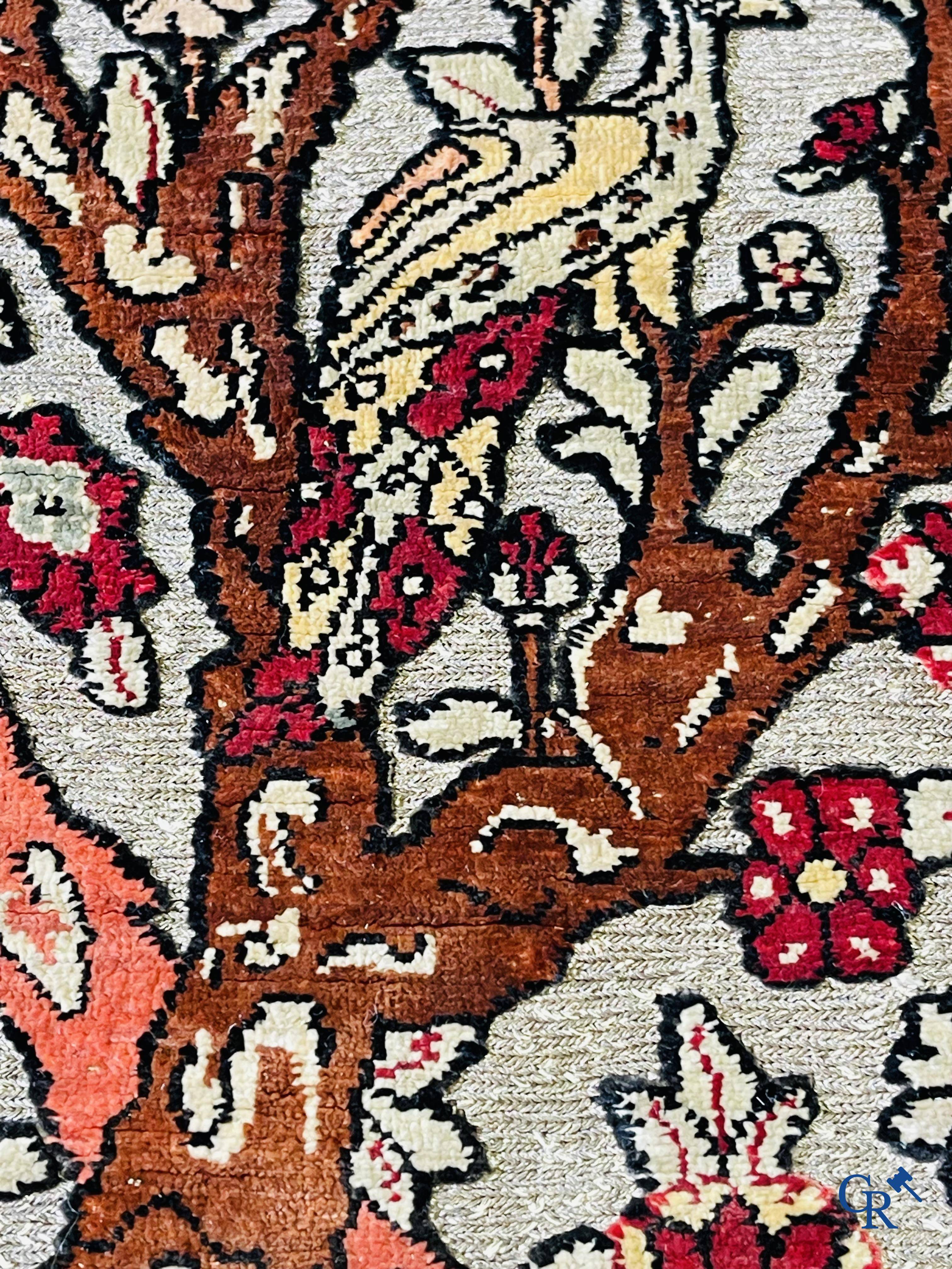 Oriental carpets, a hand-knotted carpet in silk with forest animals in a floral decor on a background in gold thread.