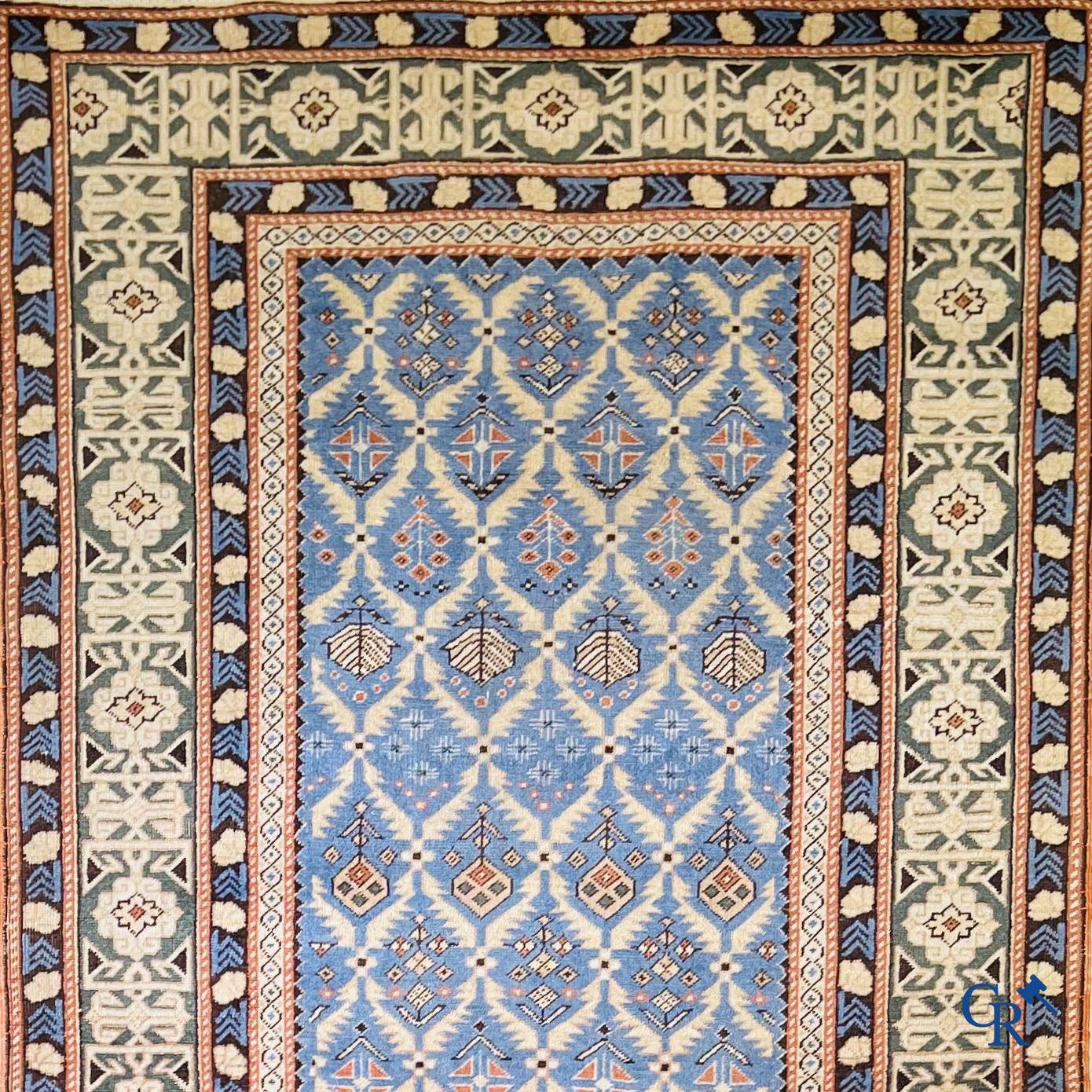 Antieke Oosterse tapijten, een antiek Dagestan tapijt met motieven op een blauwe achtergrond.