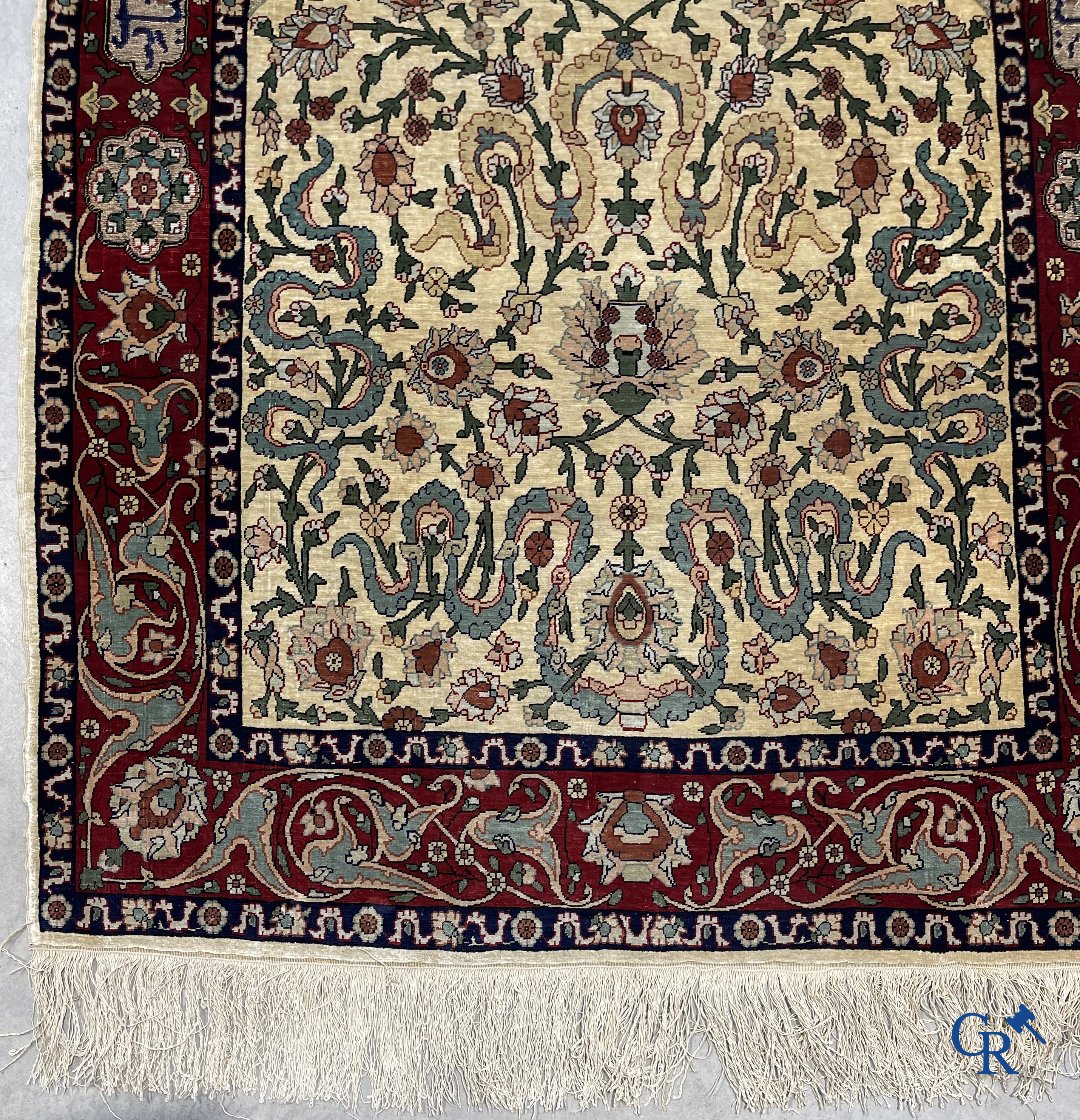 Oosterse tapijten. Een zijden gesigneerd tapijt op donkerrode achtergrond. Inscripties en bewerkt met gouddraad.