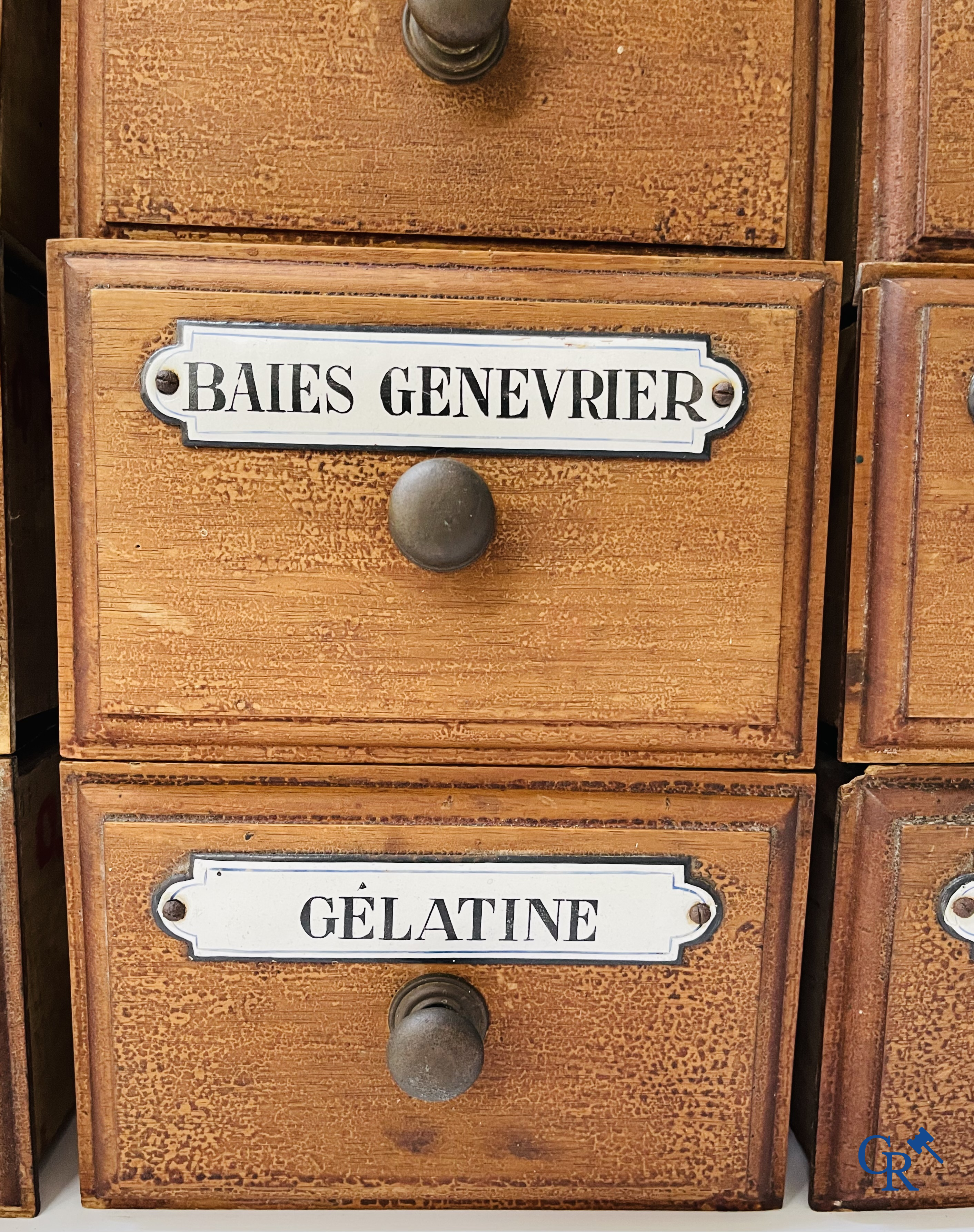 14 laden met emaille bordjes voor kruiden, specerijen en andere afkomstig van een winkelmeubel. Circa 1920.