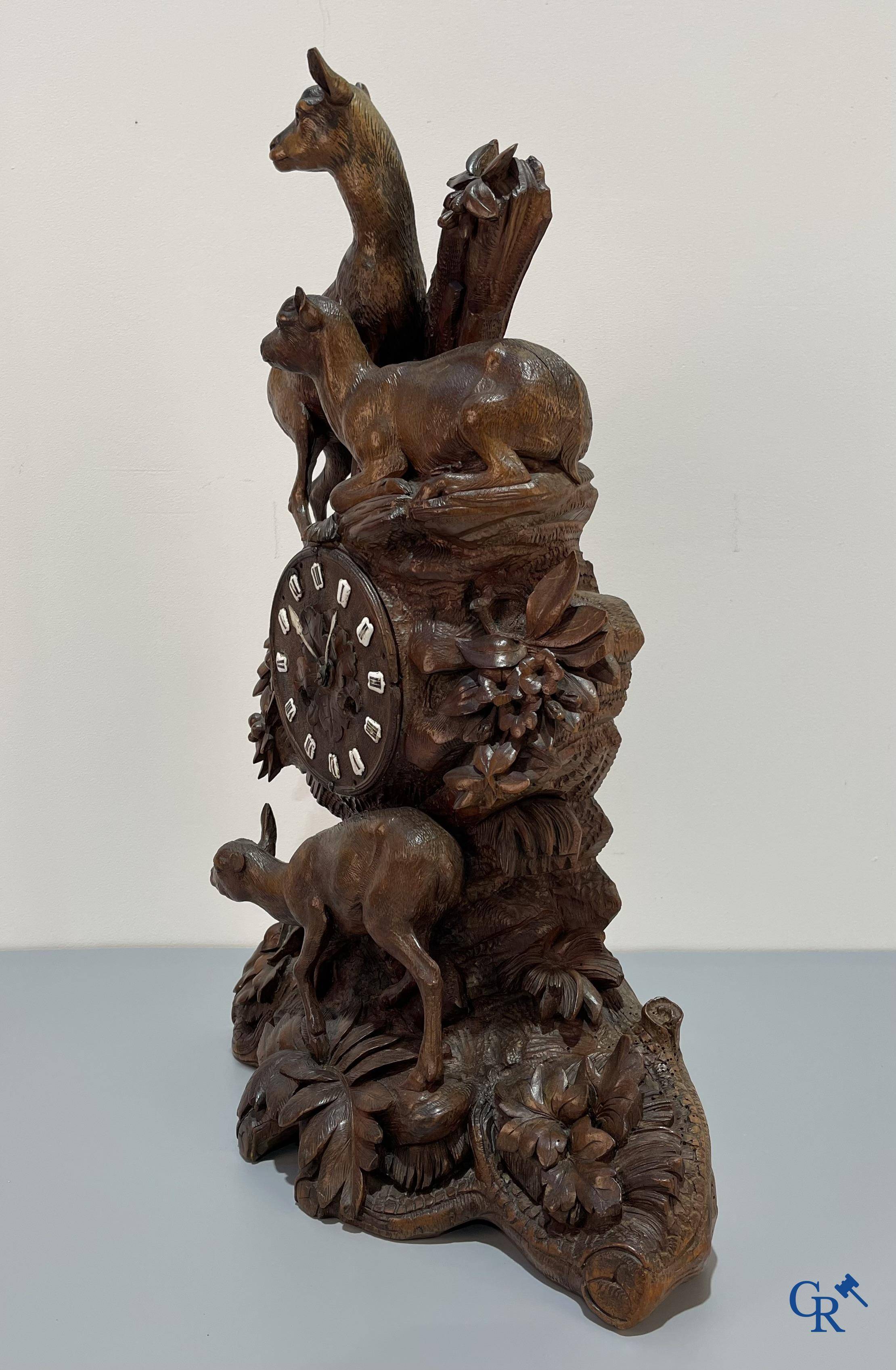 A wood sculpted Black Forest clock with deer in their flora. Germany, late 19th century.
