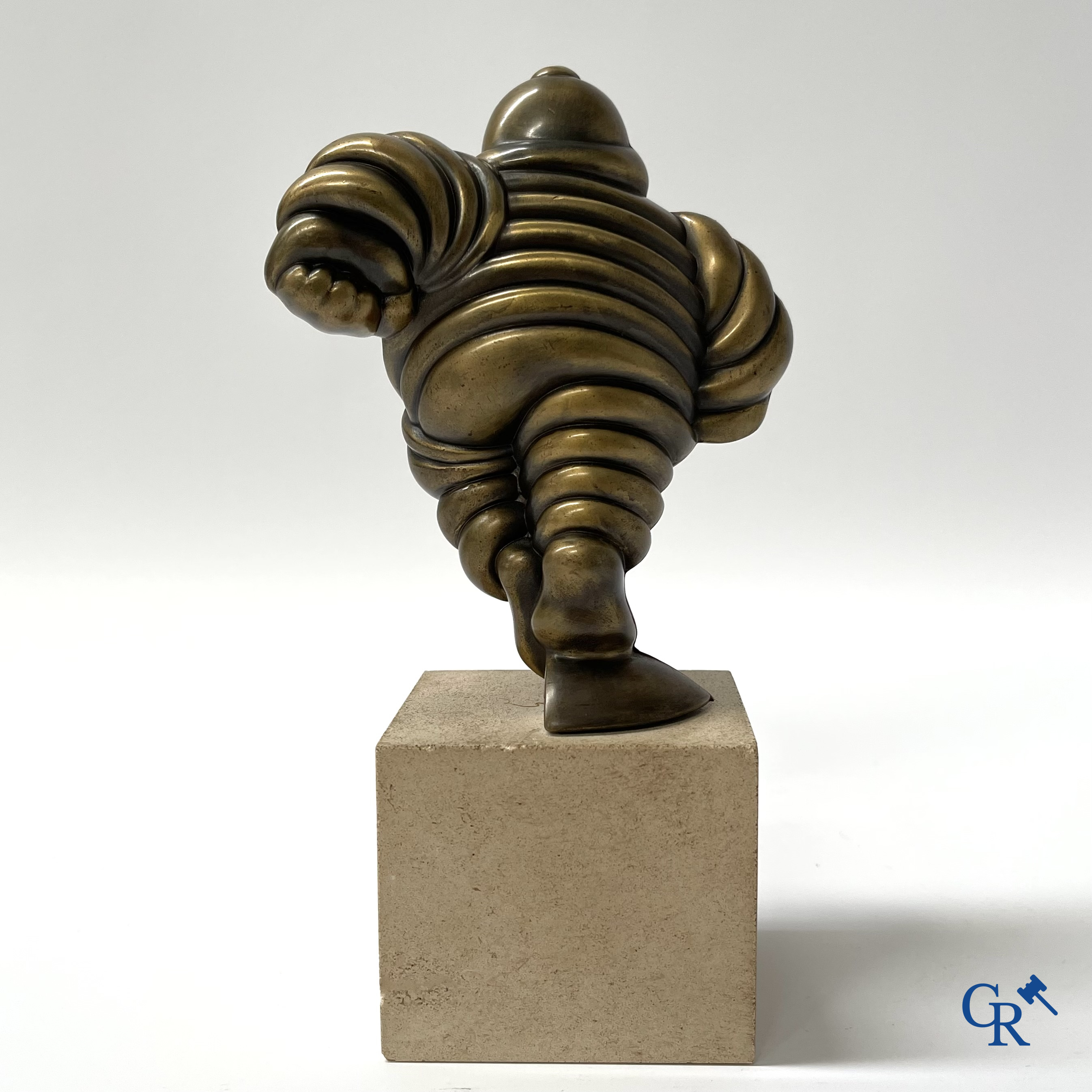 Michelin, Presentation of a running Bibendum in patinated bronze on a stone pedestal. Signed Gerard.