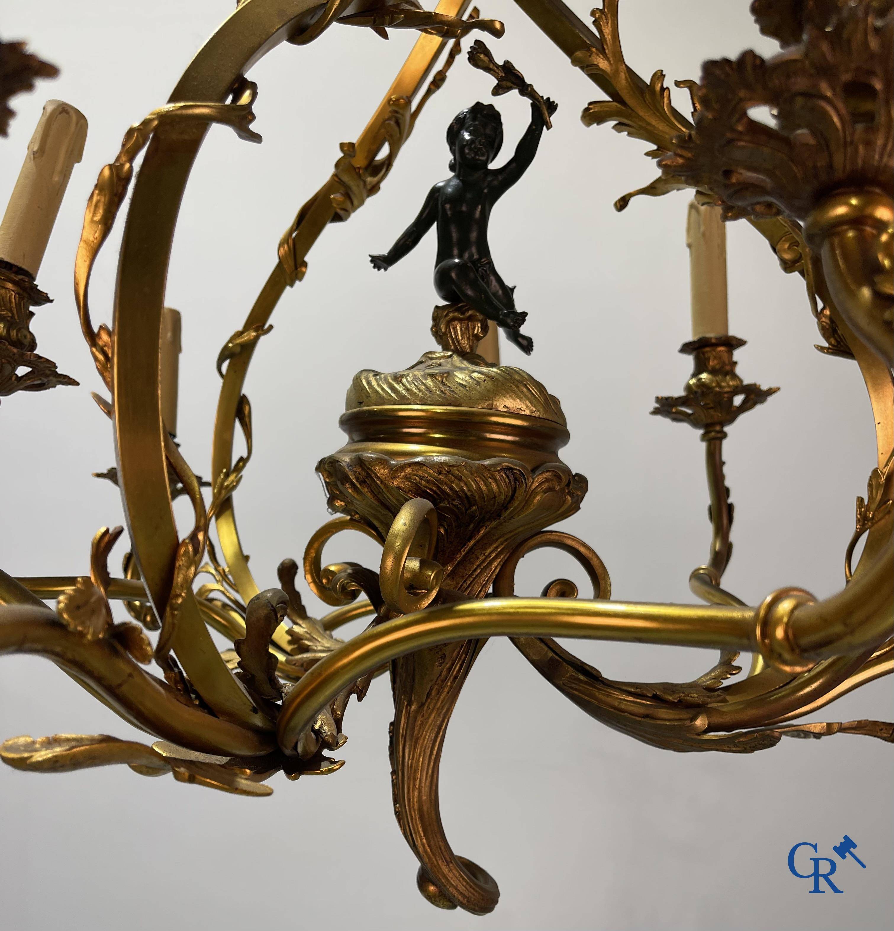 A bronze chandelier with putti and 9 light points in LXV style. Circa 1920.