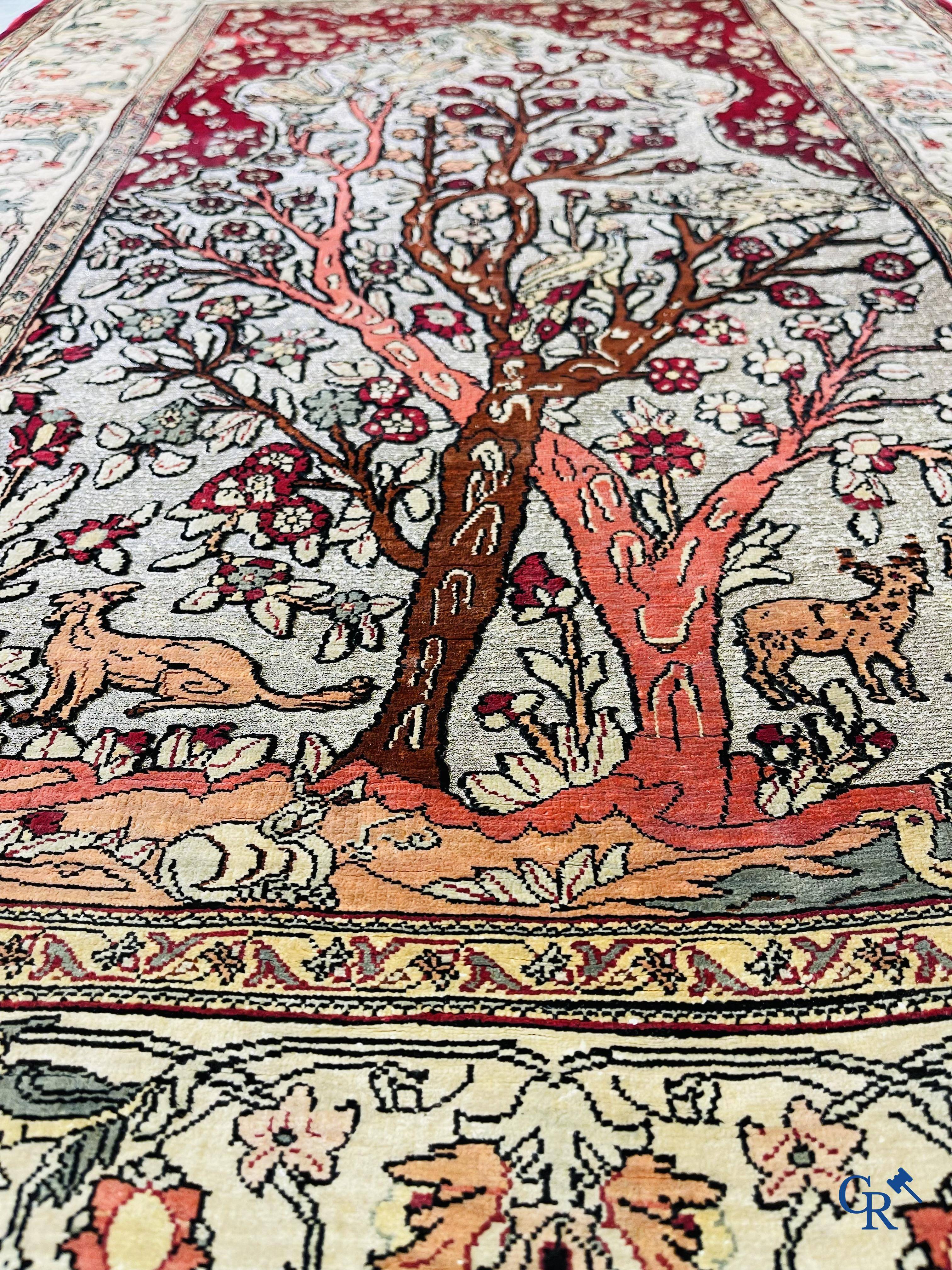 Oriental carpets, a hand-knotted carpet in silk with forest animals in a floral decor on a background in gold thread.