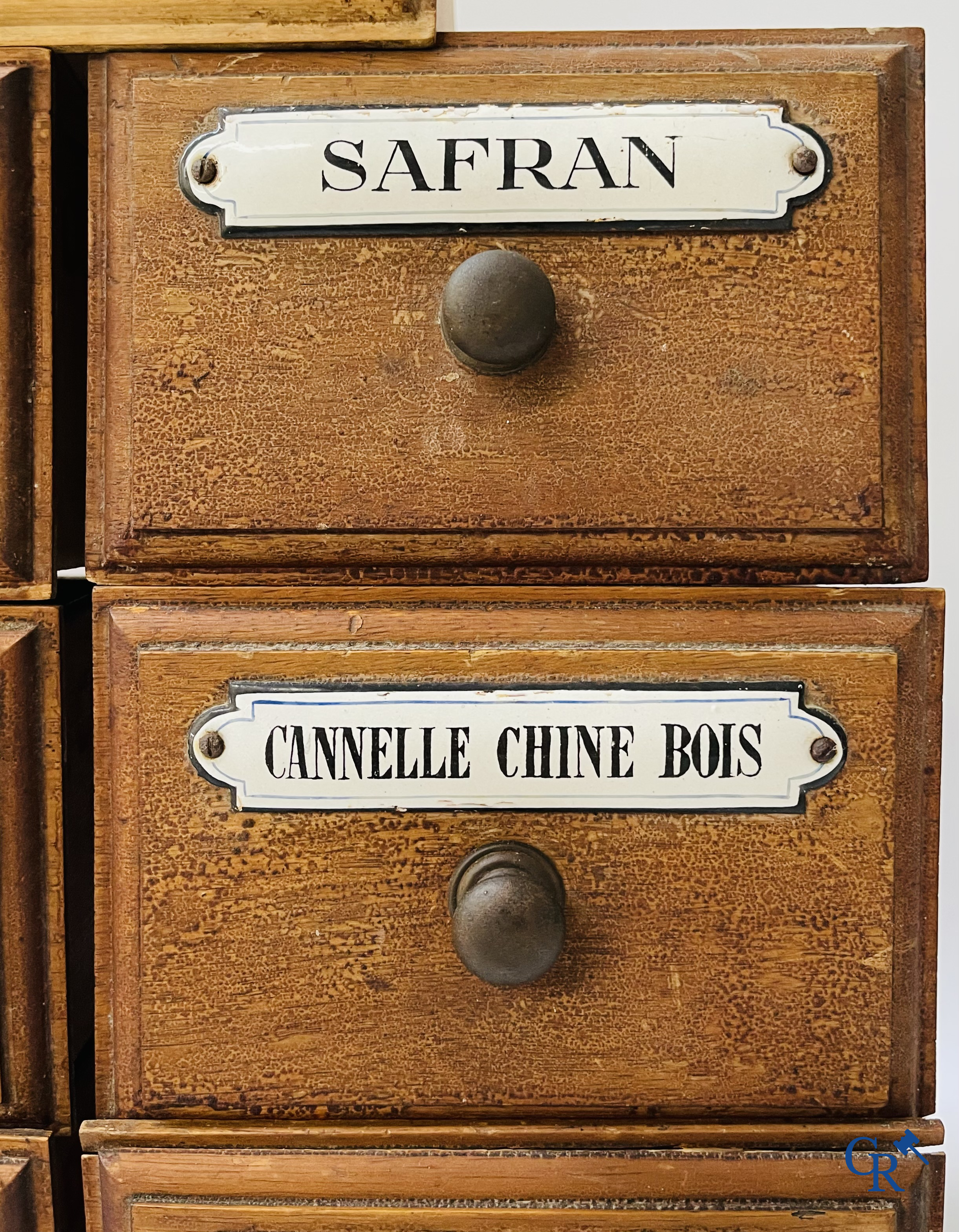 14 laden met emaille bordjes voor kruiden, specerijen en andere afkomstig van een winkelmeubel. Circa 1920.