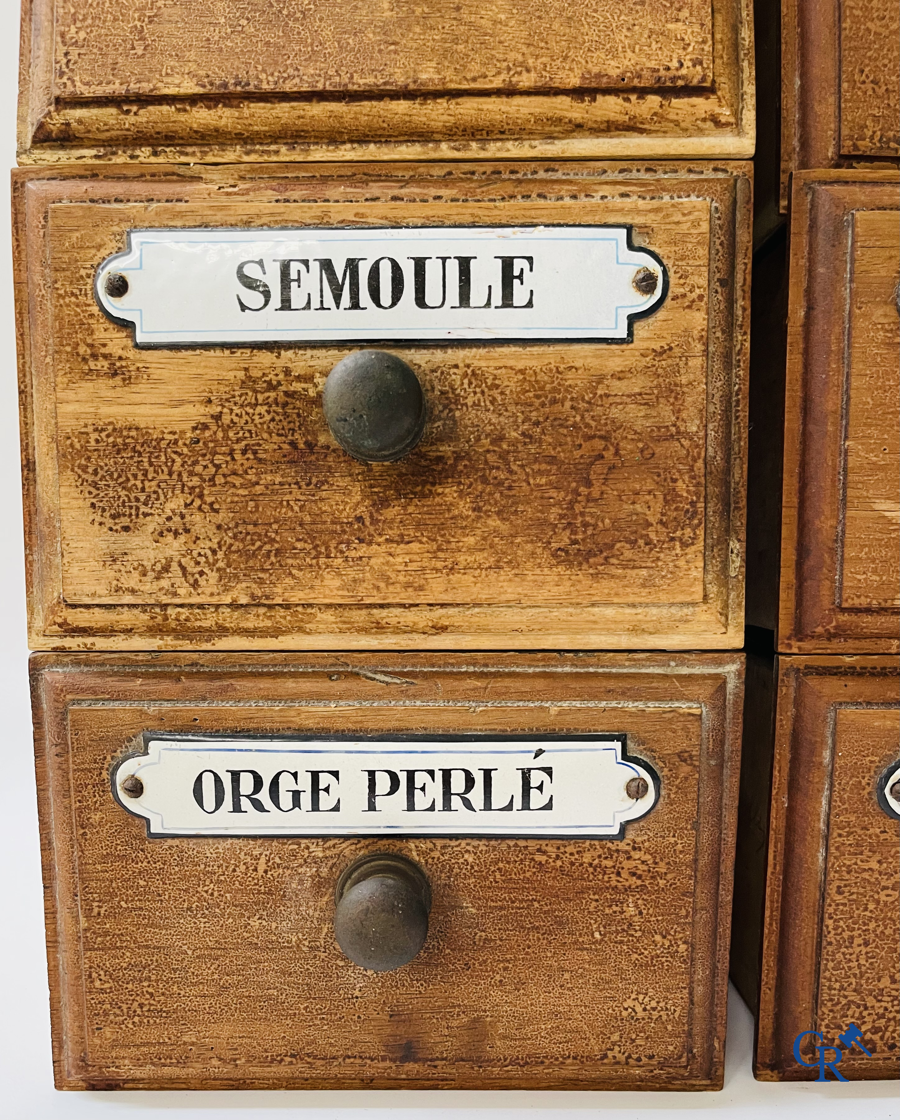 14 laden met emaille bordjes voor kruiden, specerijen en andere afkomstig van een winkelmeubel. Circa 1920.