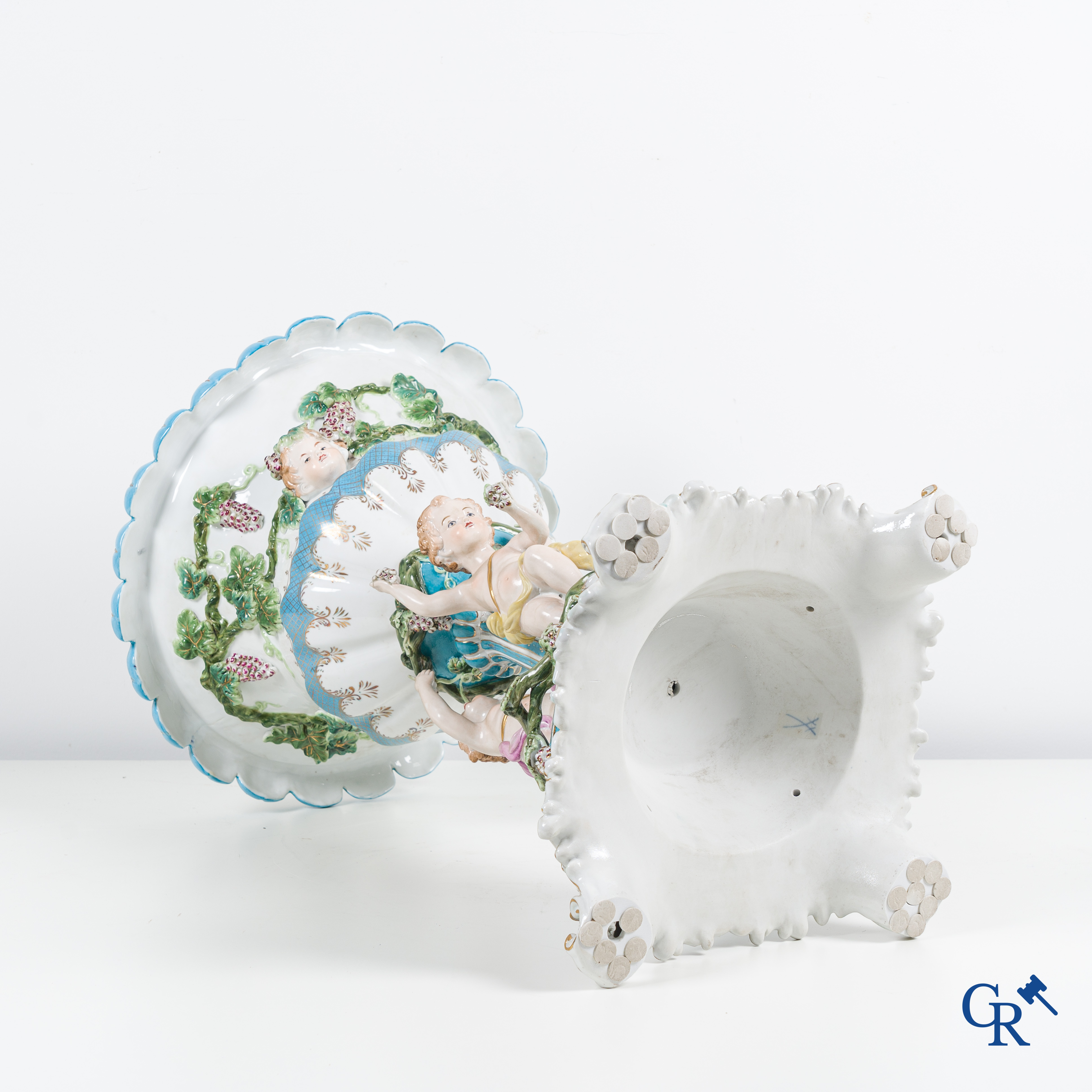 Een grote pronkcoupe in porselein met putti, druivenranken en bacchus hoofden. 20ste eeuw.
