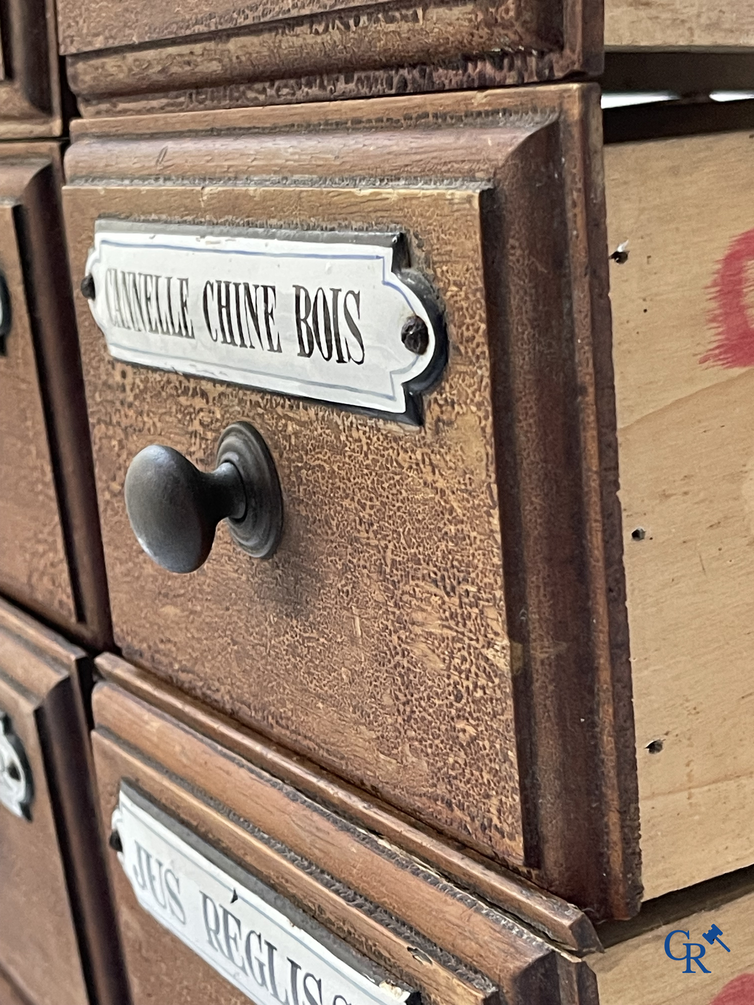 14 laden met emaille bordjes voor kruiden, specerijen en andere afkomstig van een winkelmeubel. Circa 1920.