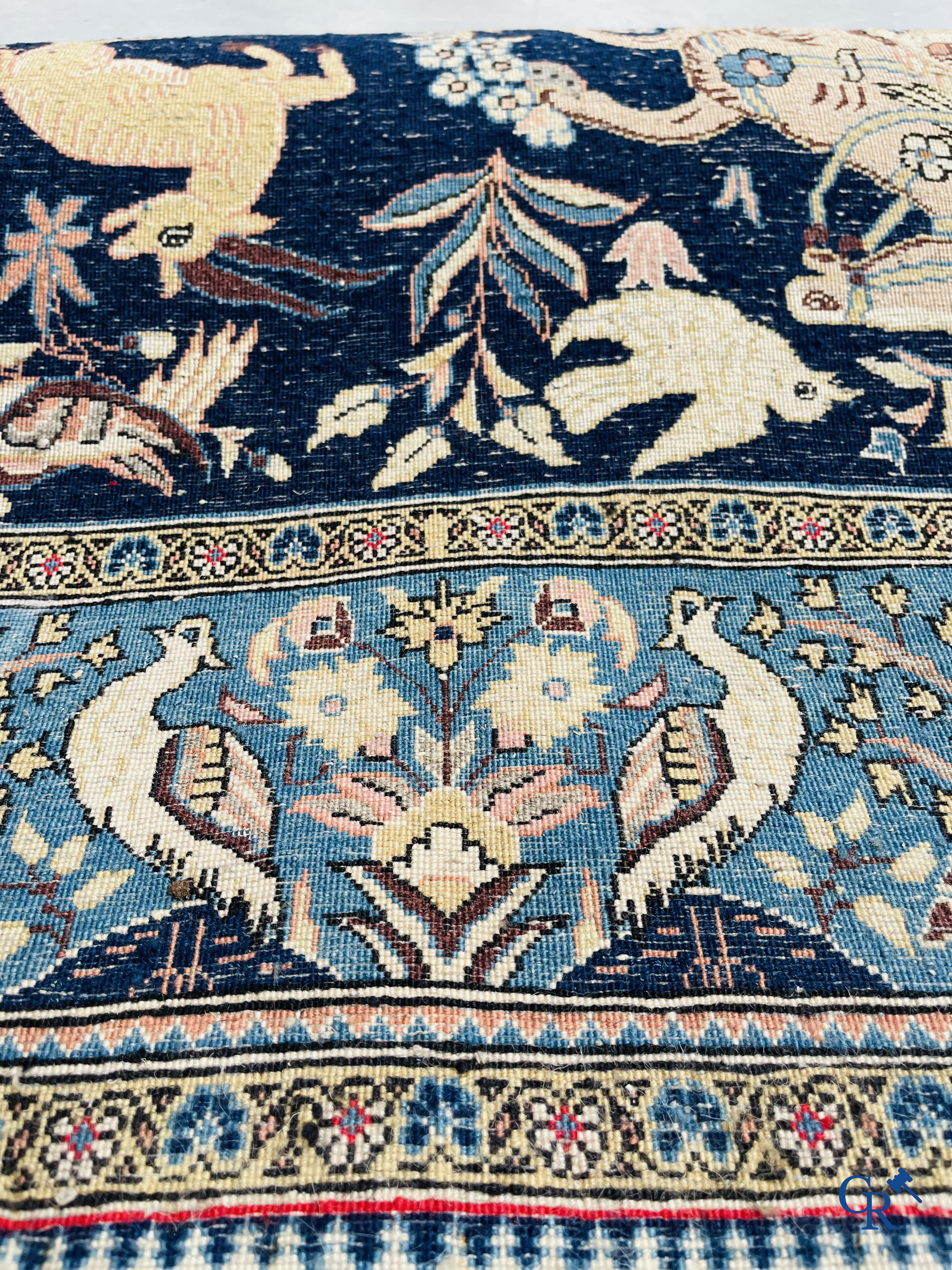 Oosterse tapijten. Ghoum, een fijn geknoopt Perzisch tapijt met ruiters te paard op een donkerblauwe achtergrond.