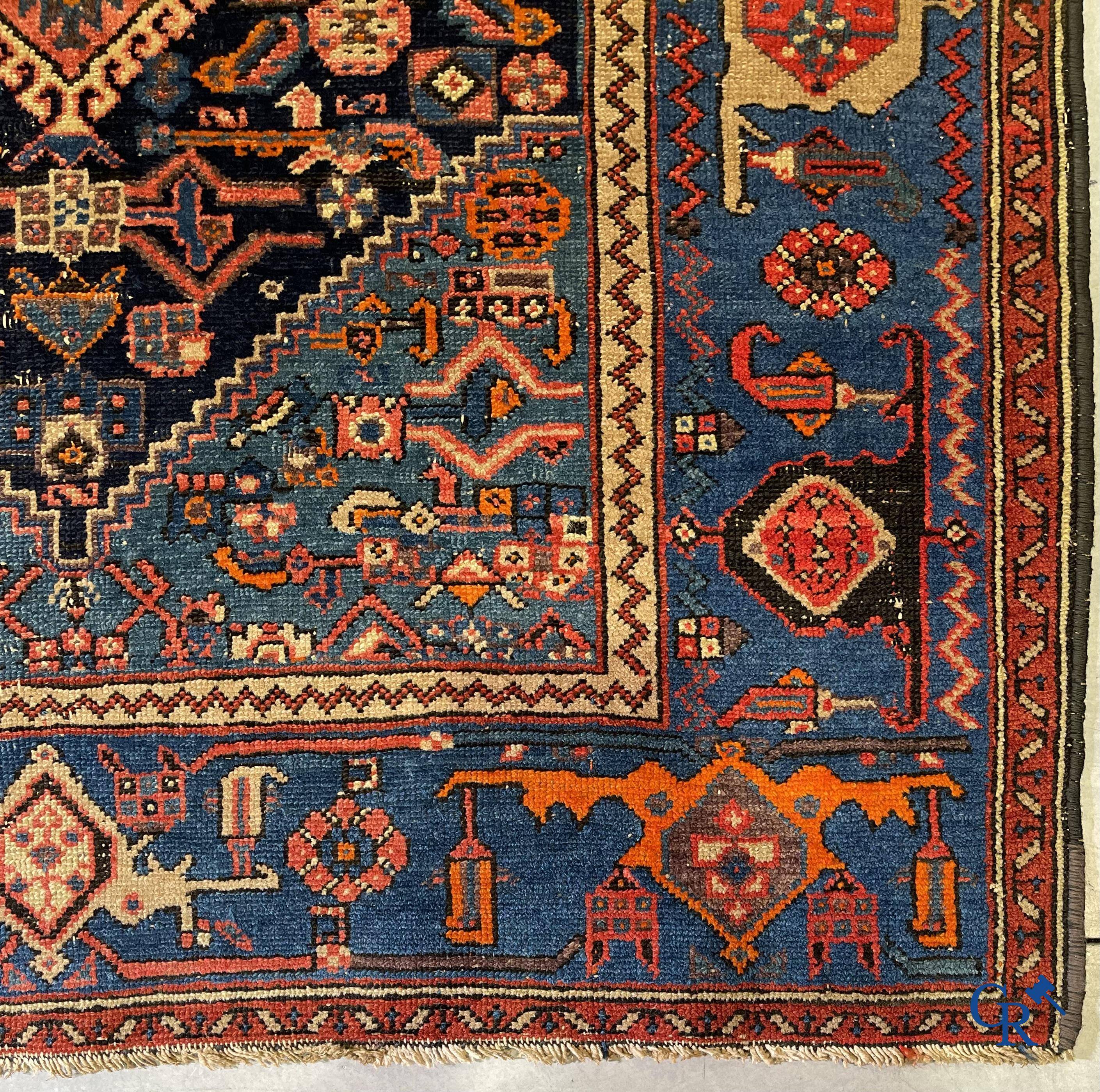 Antieke Oosterse tapijten, een antiek handgeknoopt tapijt met motieven op een blauwe achtergrond.