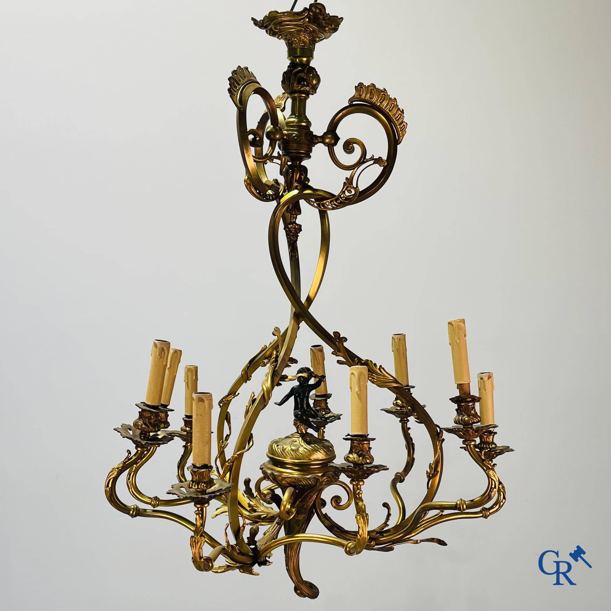 A bronze chandelier with putti and 9 light points in LXV style. Circa 1920.